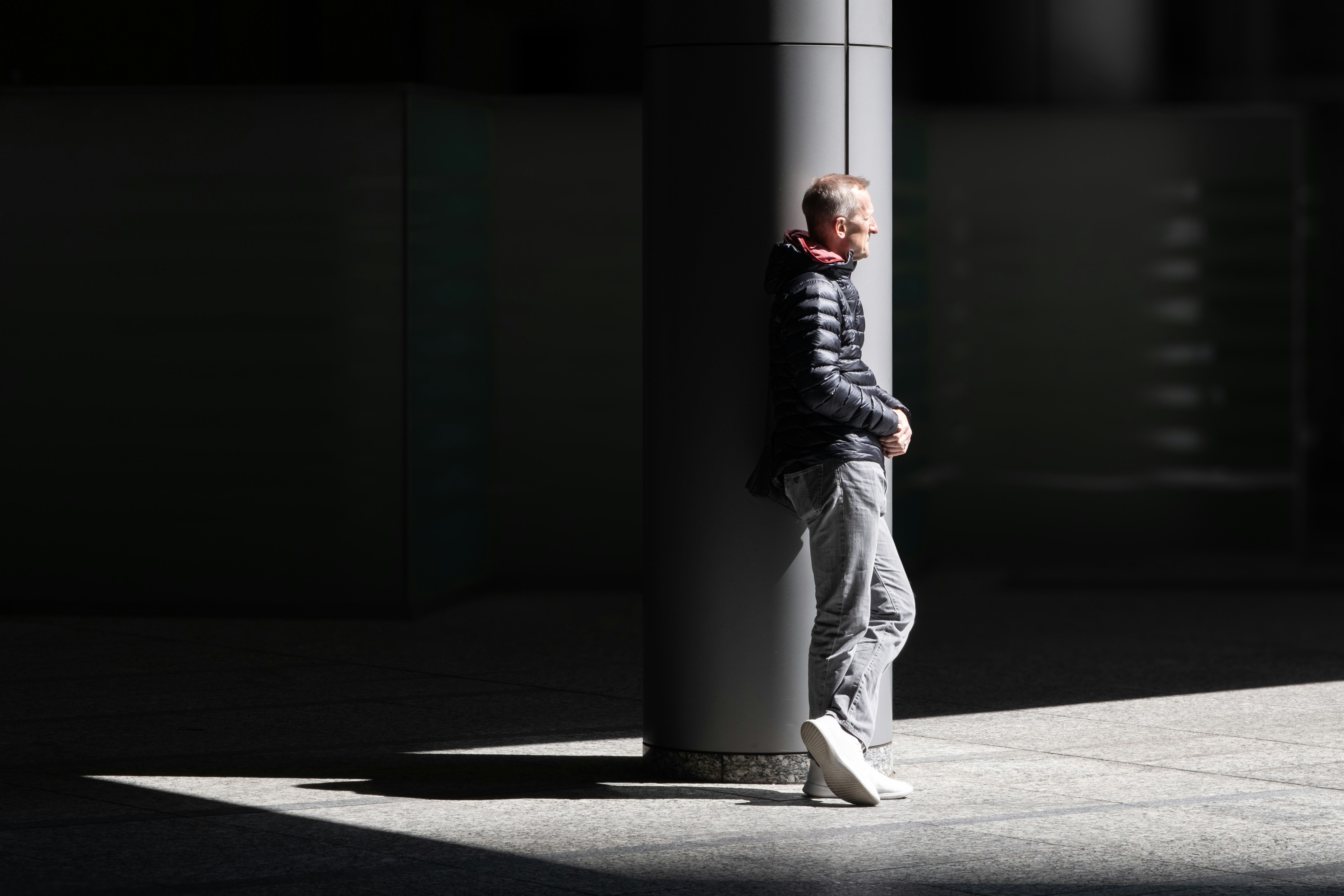 A man leaning against a pole on a sidewalk