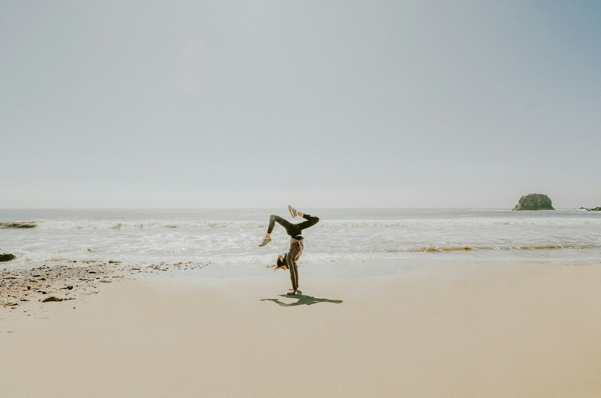A woman standing on top of a sandy beach