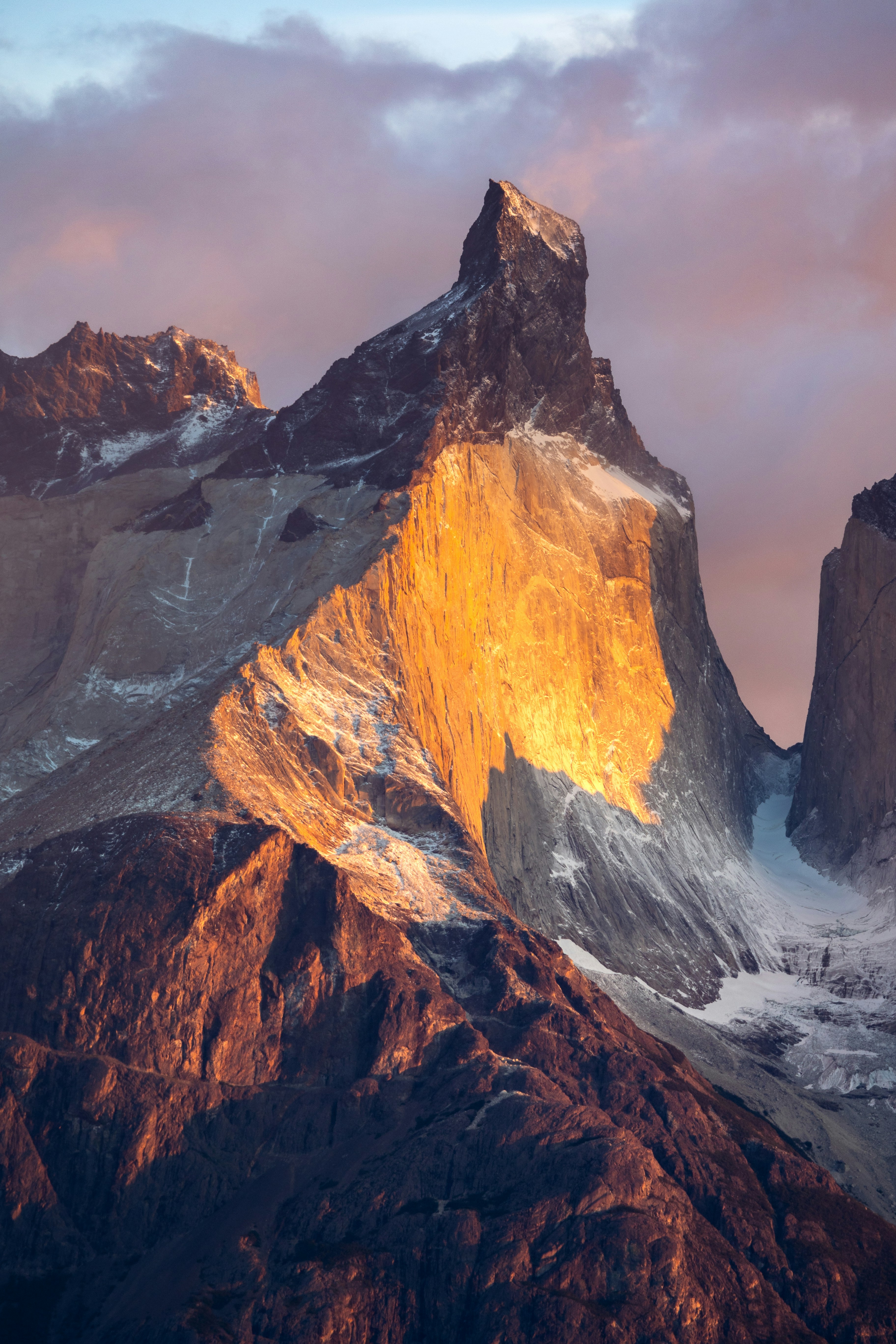 A very tall mountain covered in snow under a cloudy sky