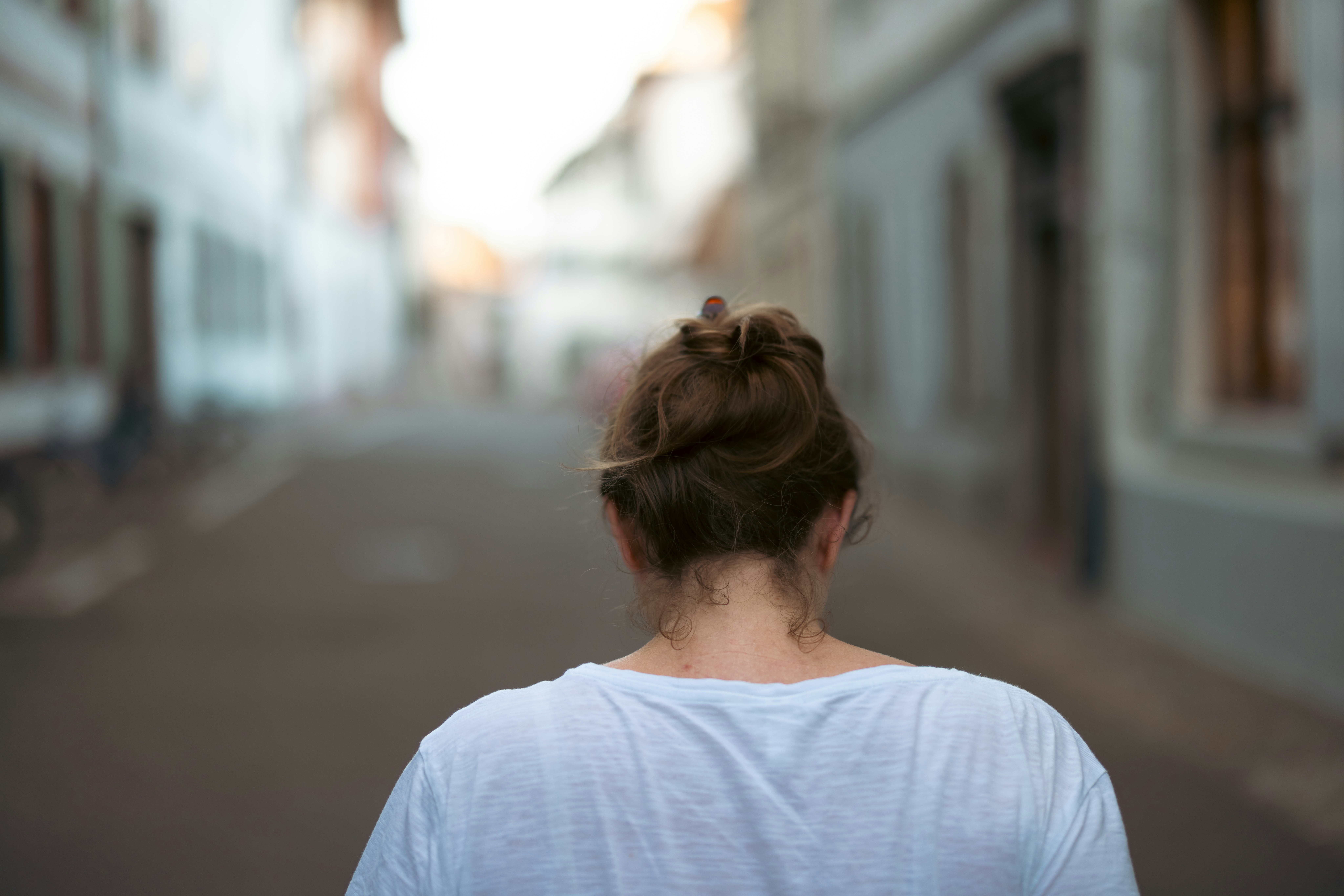 A woman walking down a street next to tall buildings