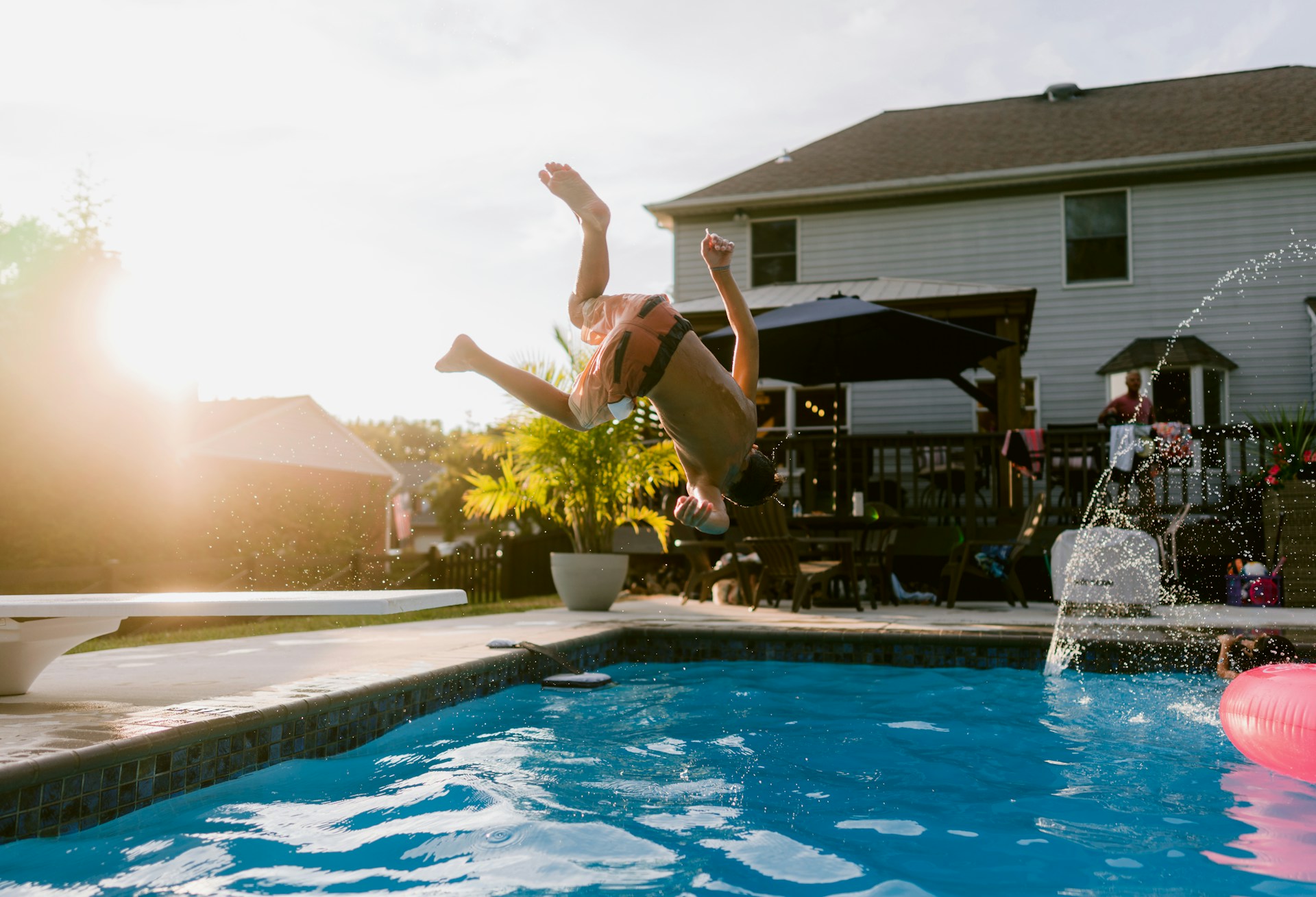 A person jumping into a pool with a frisbee