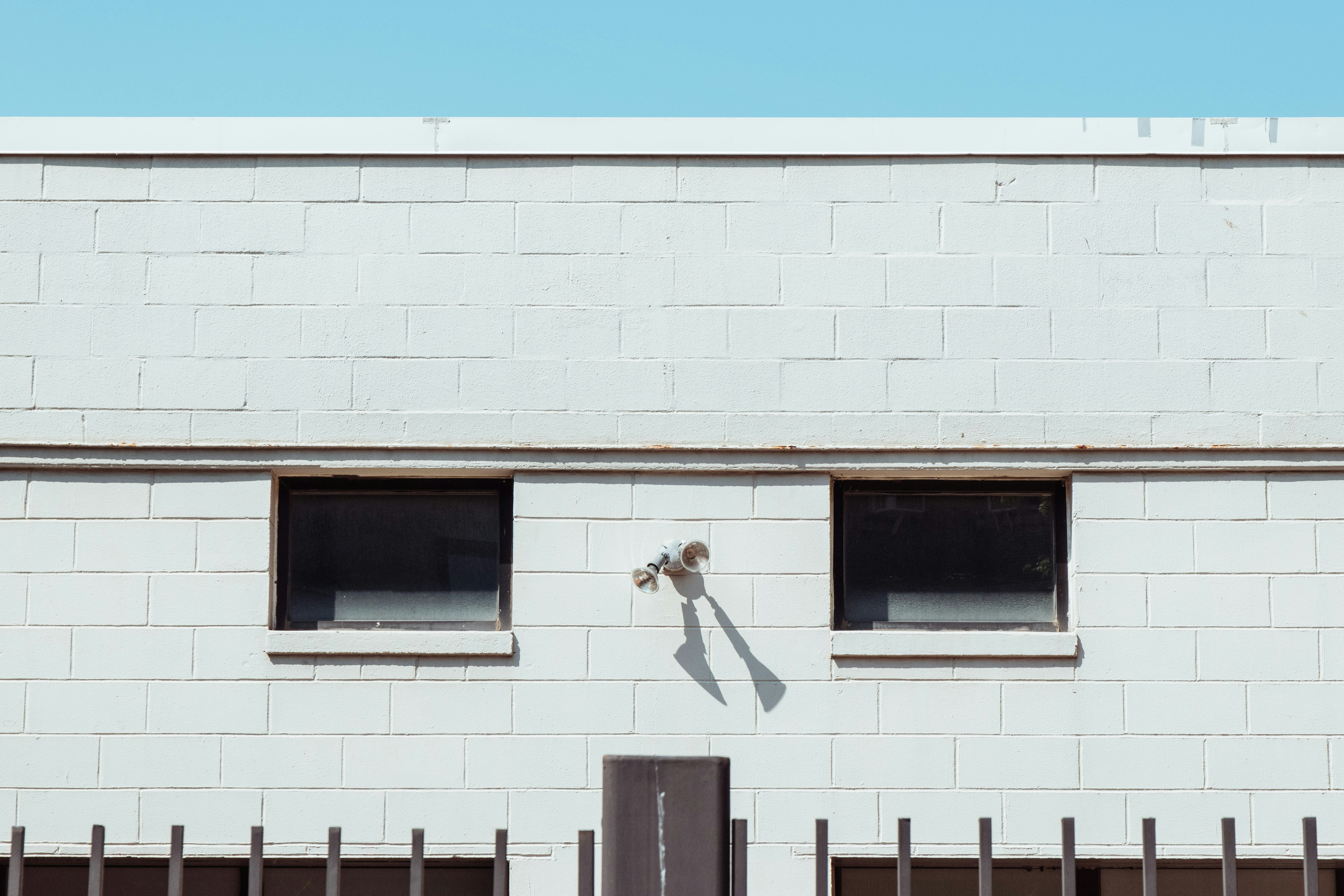 Um edifício branco com duas janelas e um portão preto
