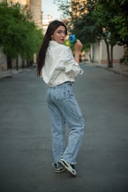 A woman standing on a street with a bottle in her hand