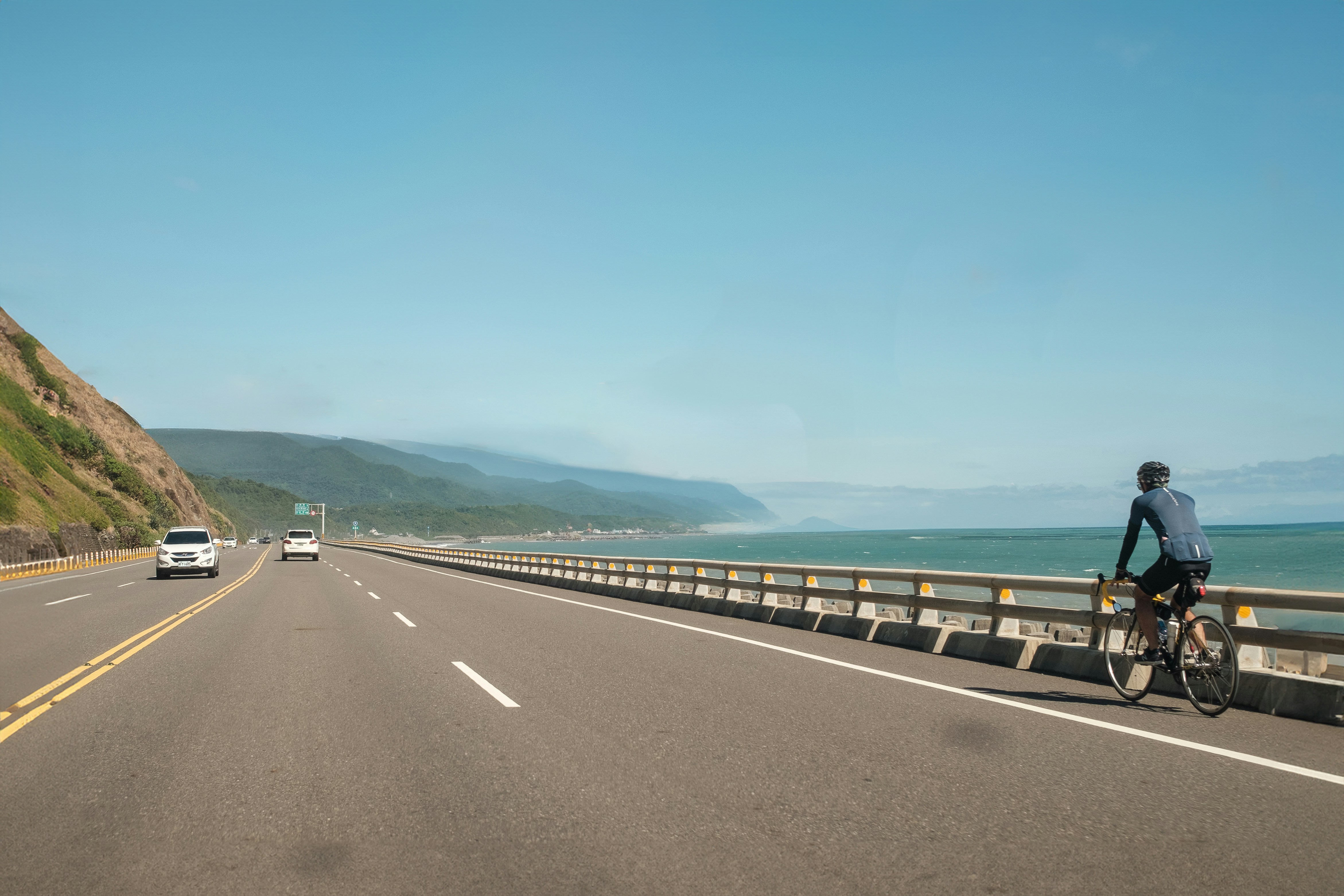 A man riding a bike down a highway next to the ocean