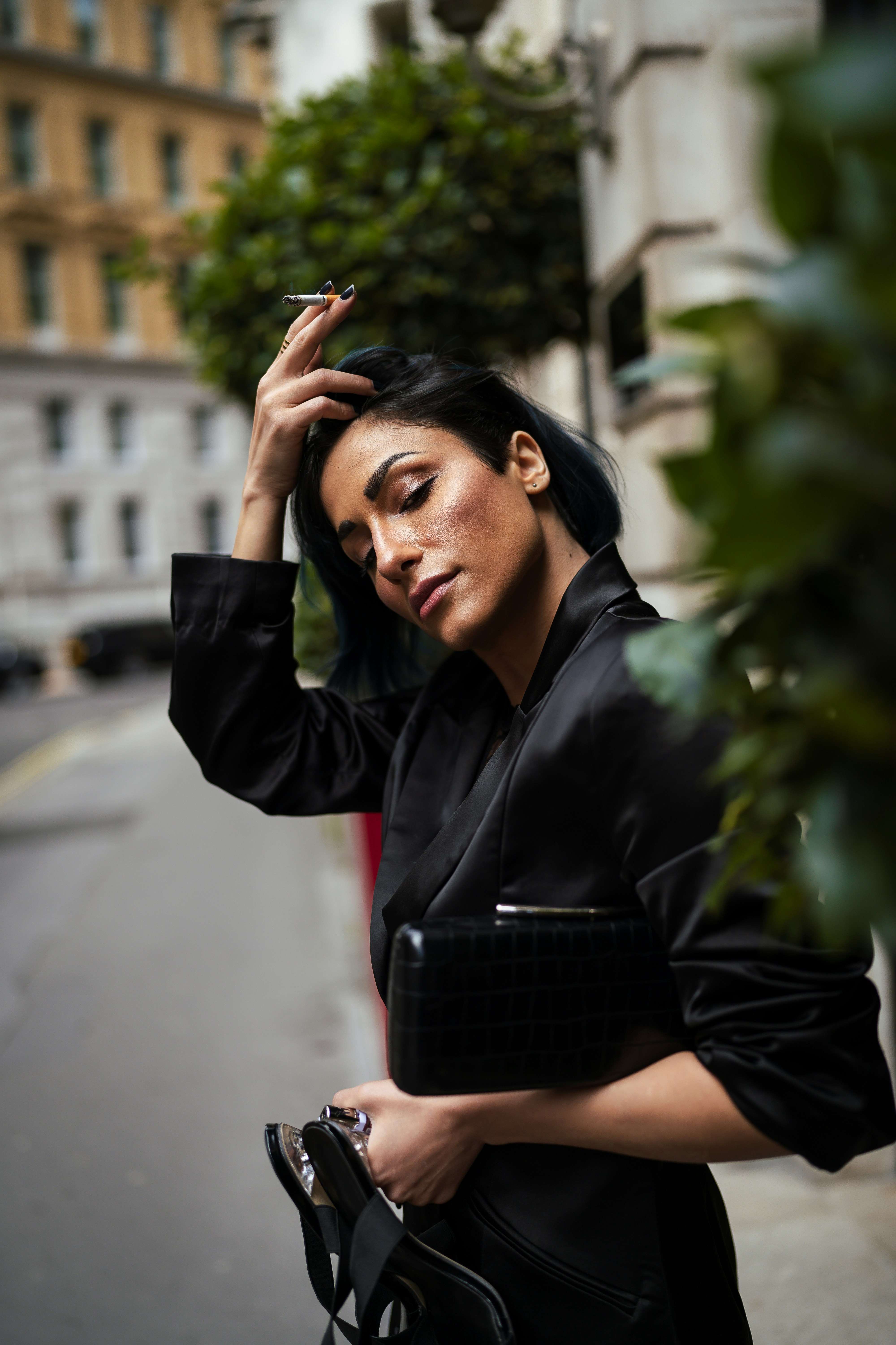 A woman in a black dress smoking a cigarette