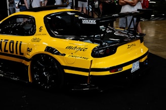A yellow race car parked in front of a crowd of people