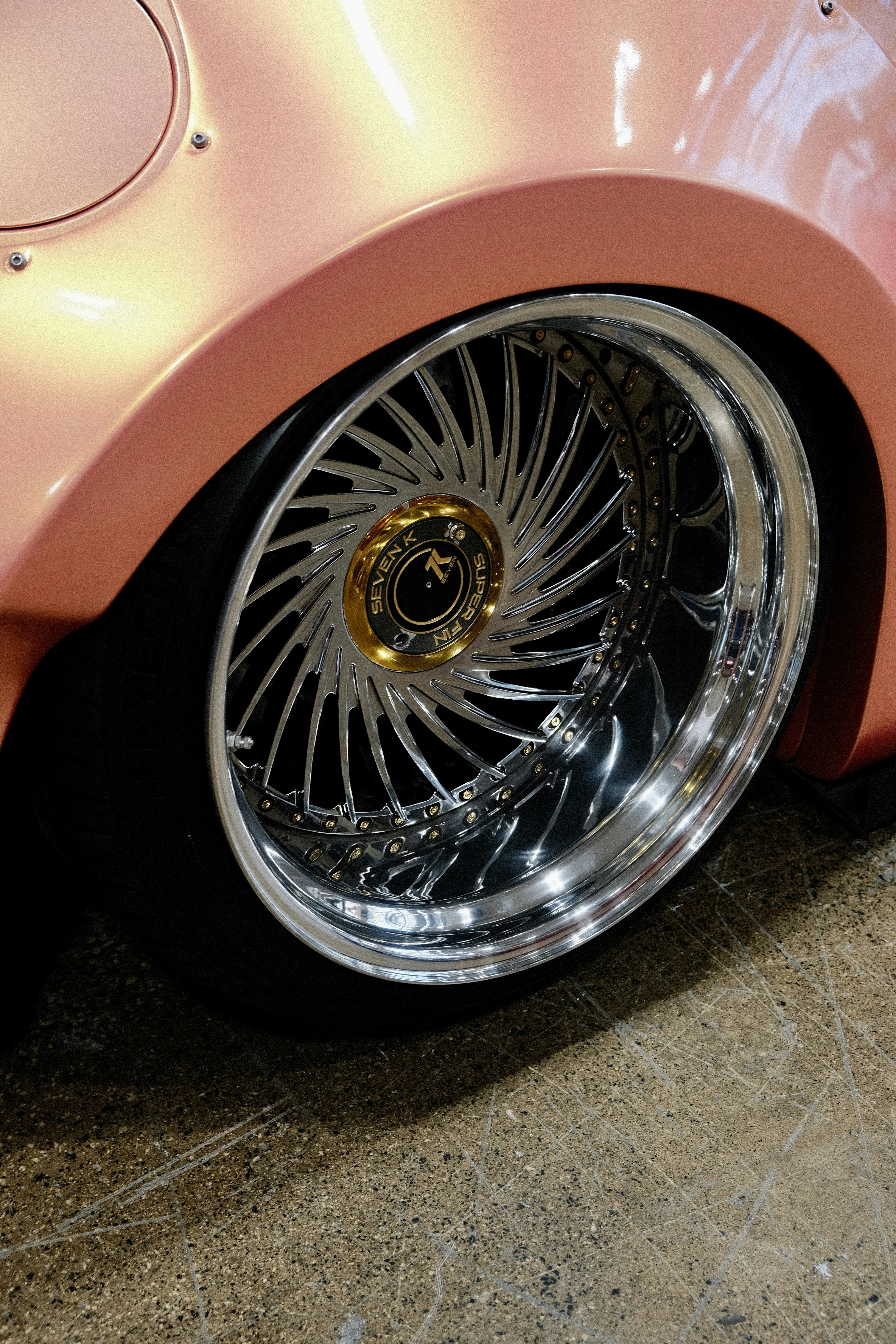 A pink car with chrome rims parked in a garage
