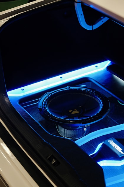 Close-up of a Kicker-branded car subwoofer installed in an enclosure with blue LED lighting showing cone and surround detail