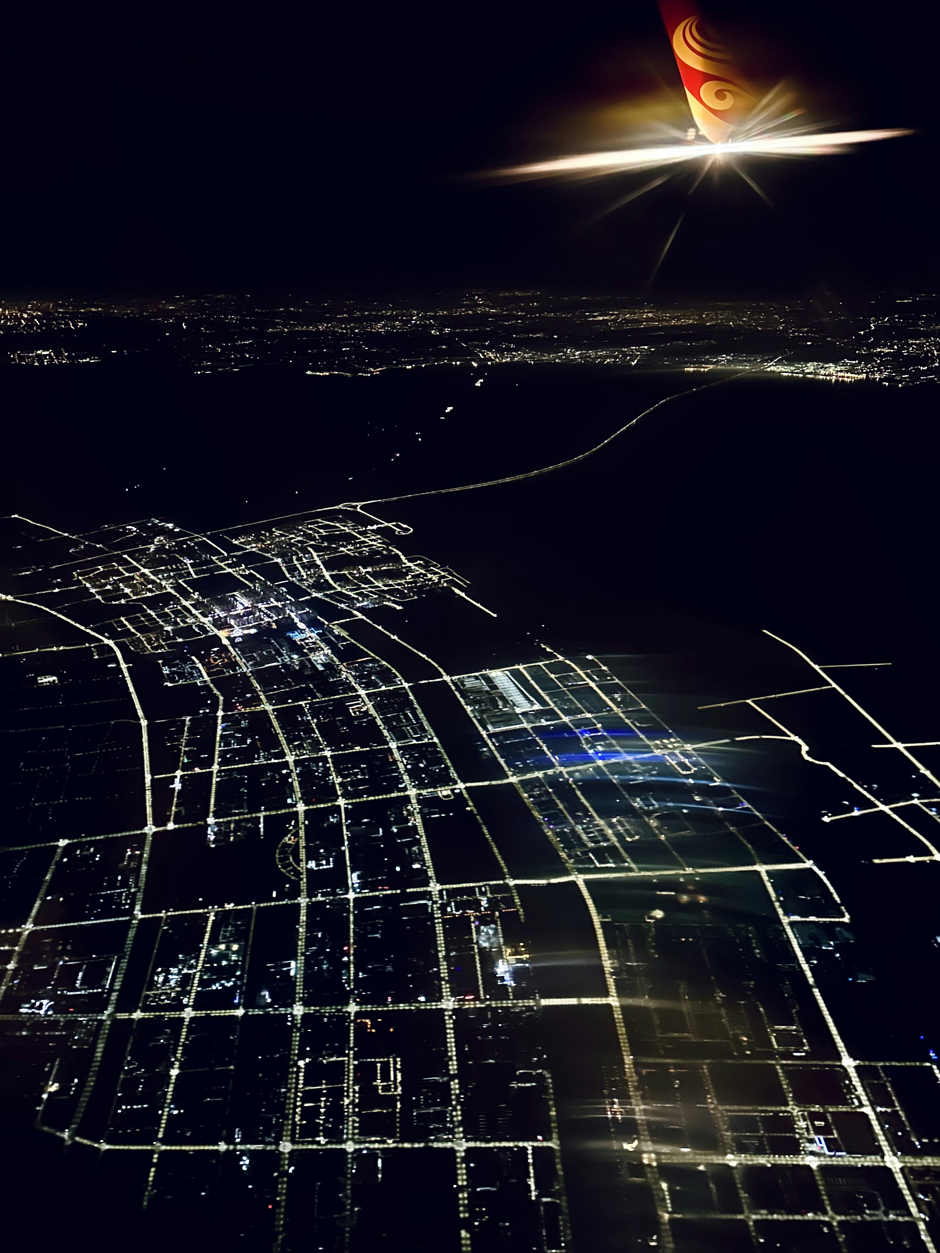 Aerial city grid at night with illuminated infrastructure networks, dark atmospheric bird's eye view