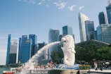 A statue of a dog spewing water in front of a city skyline