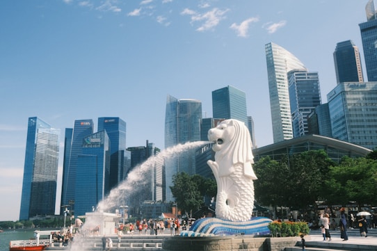 A statue of a dog spewing water in front of a city skyline
