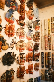 A wall full of masks hanging on a wall