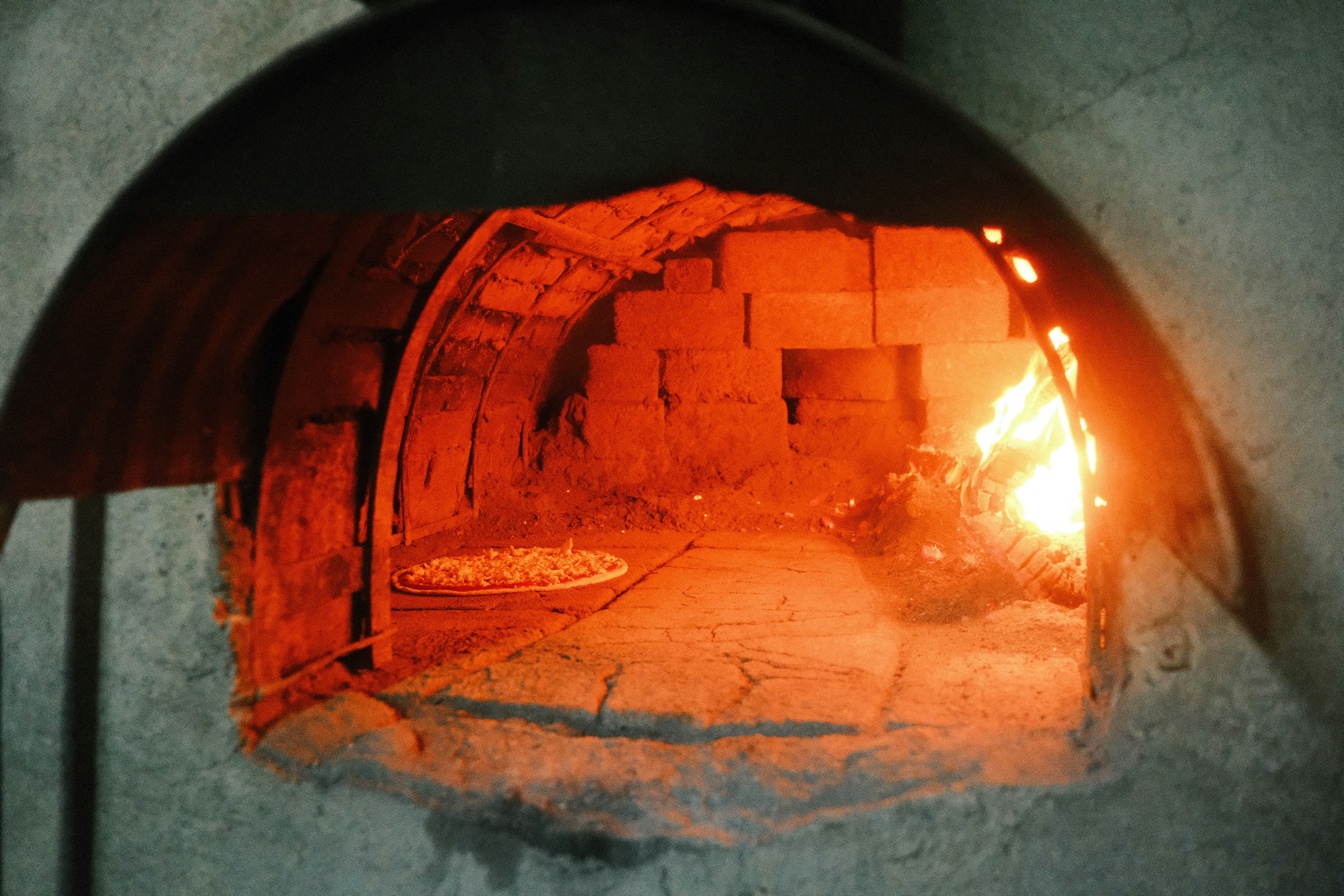 Traditional brick pizza oven with custom tile work and glowing interior - commercial pizza oven