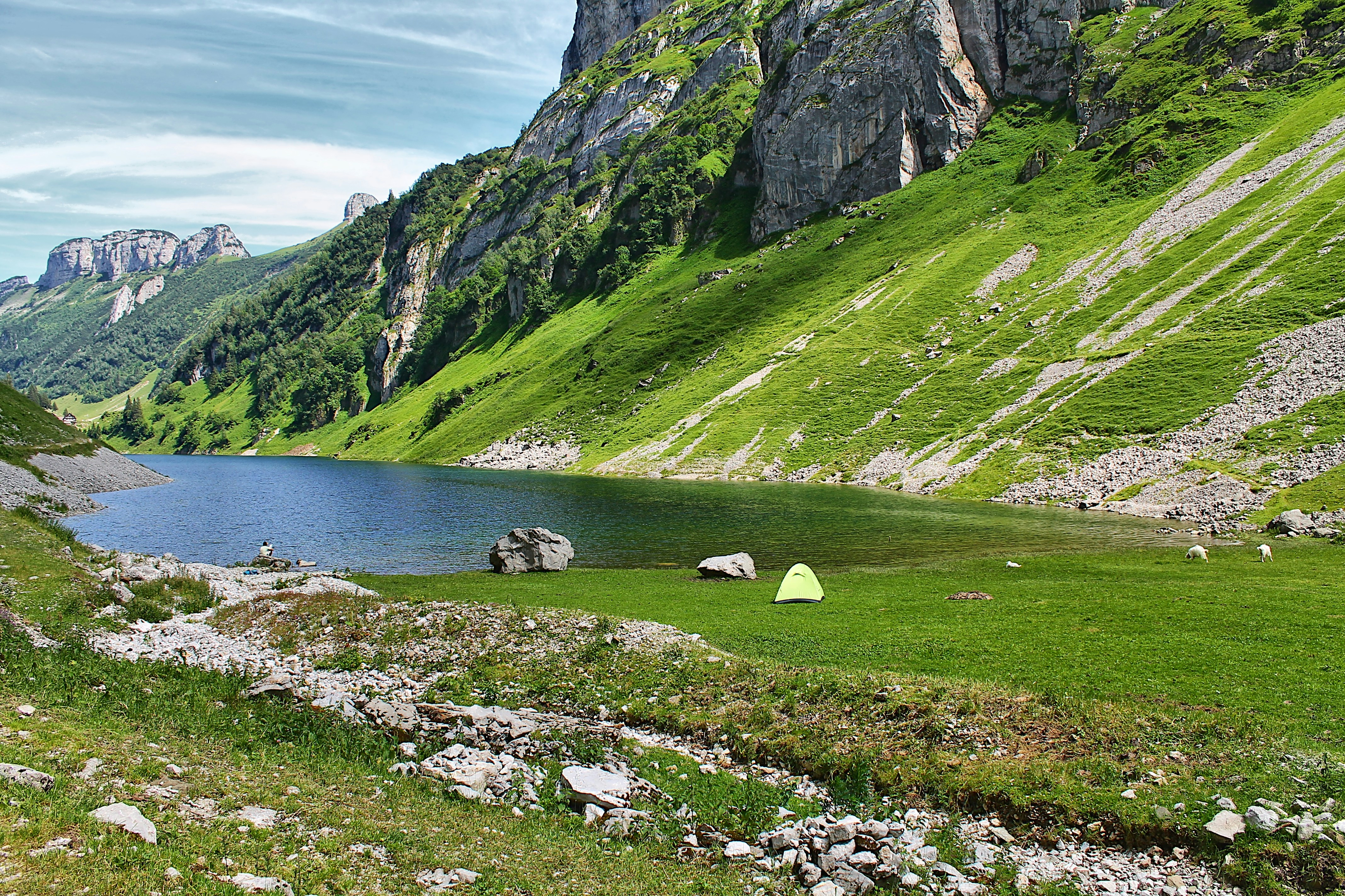 A mountain lake surrounded by green grass and rocks photo – Free ...