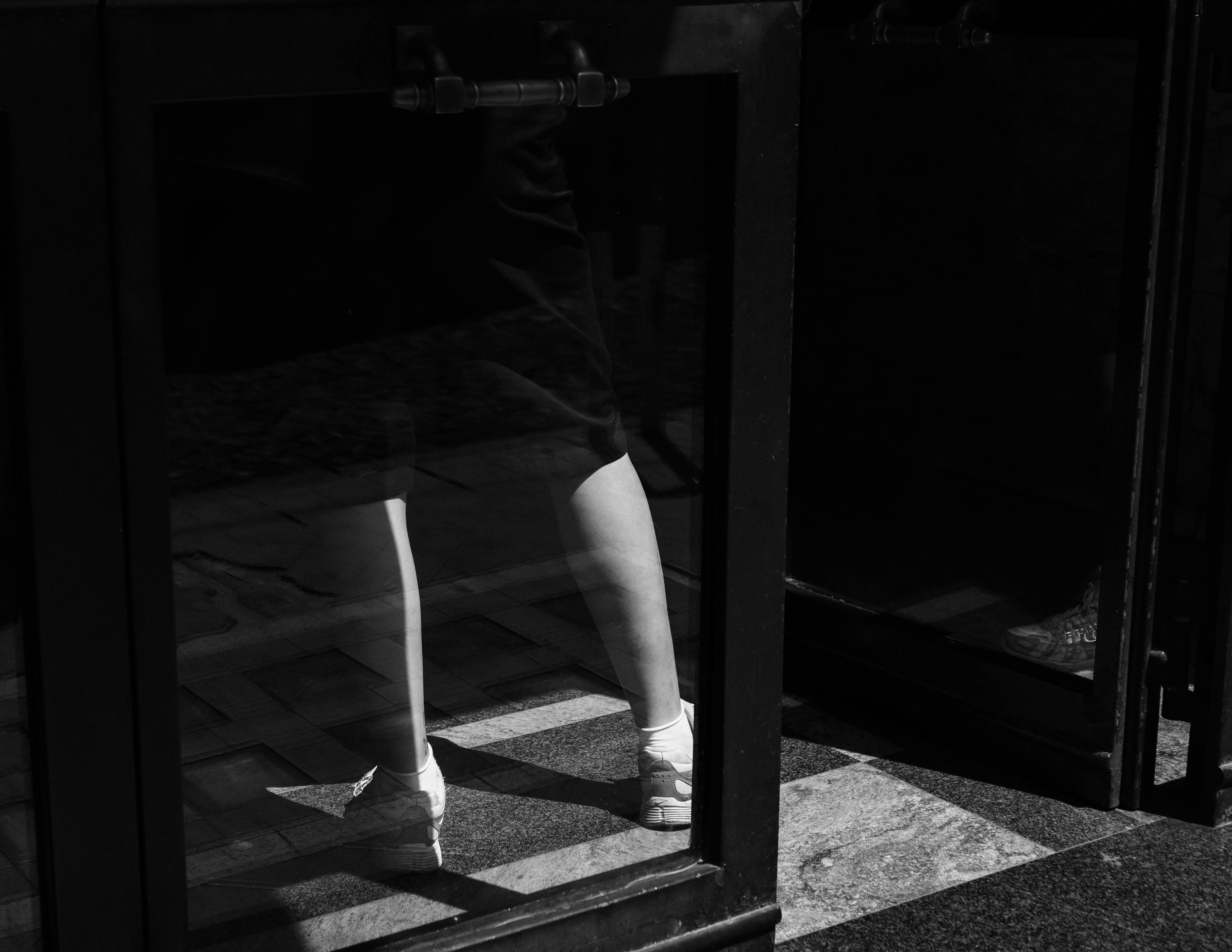 A black and white photo of a woman's legs in a mirror