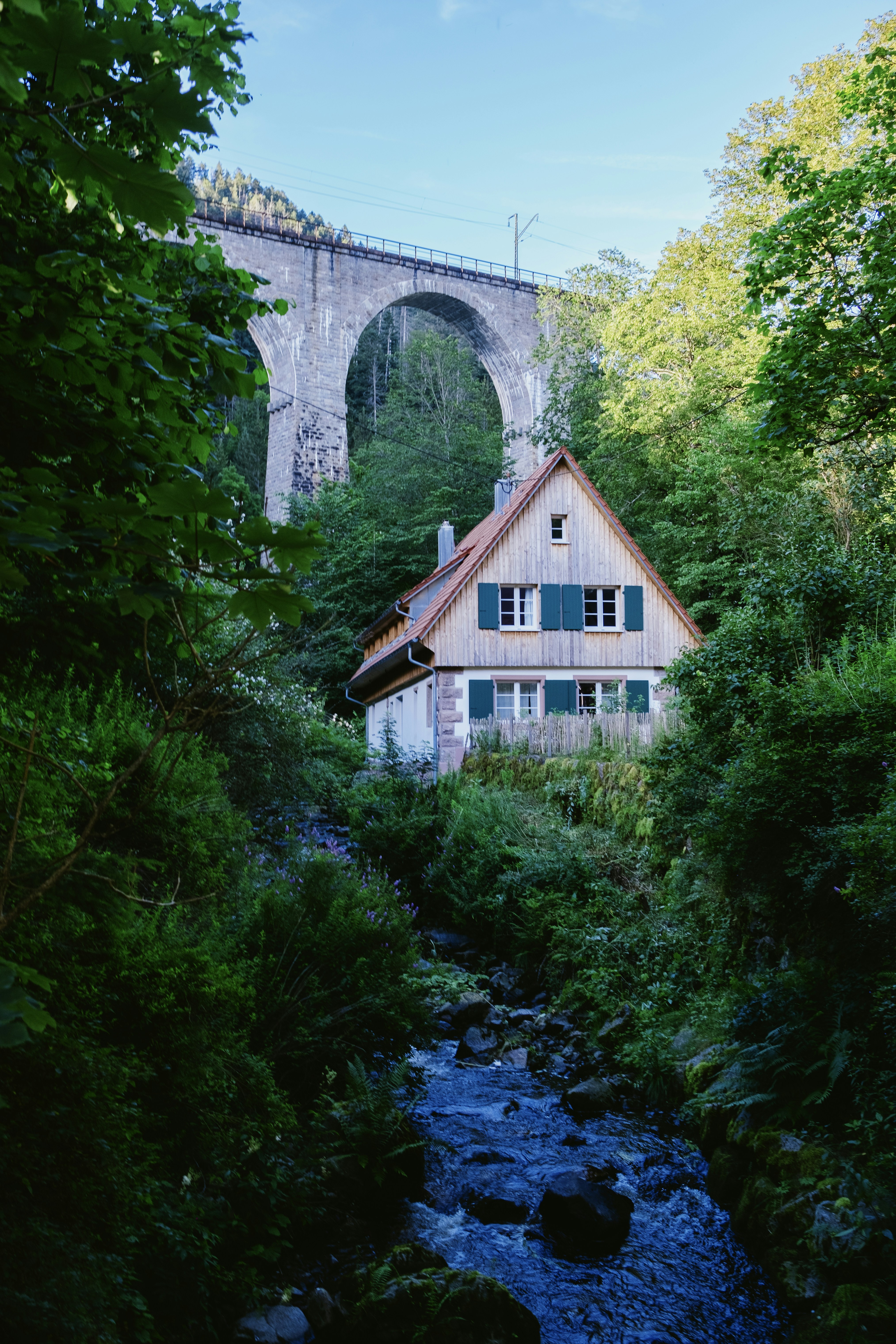 Ein Haus im Wald mit einer Brücke im Hintergrund