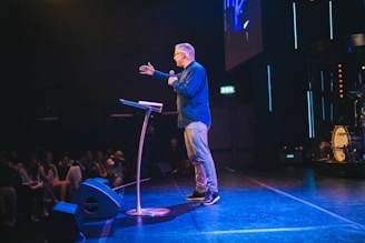 A man standing on top of a stage next to a microphone
