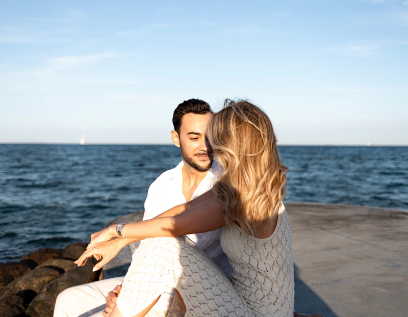 couple sitting on ocean rocks