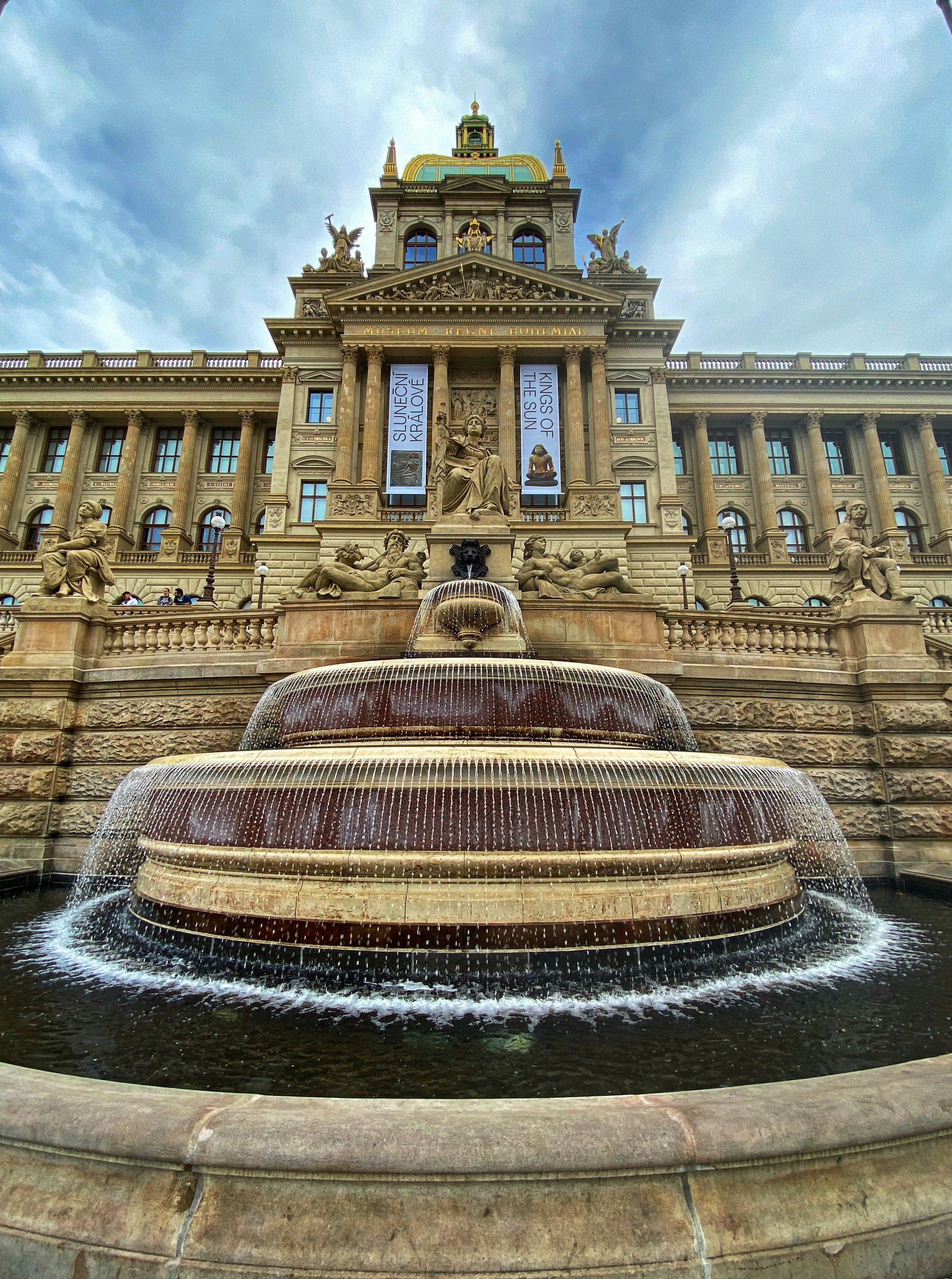 Un grand bâtiment avec une fontaine devant lui