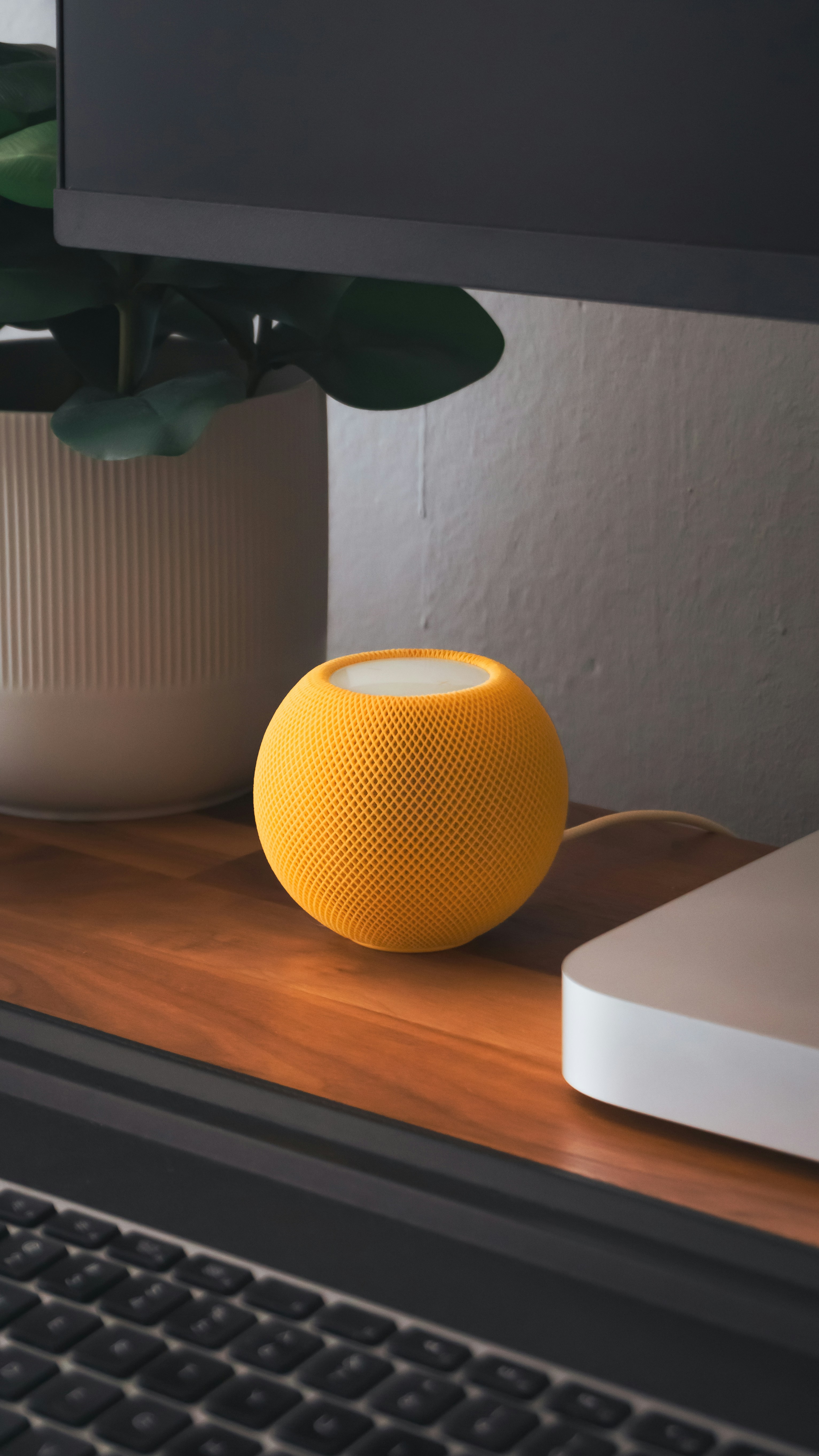 A yellow speaker sitting on top of a wooden desk