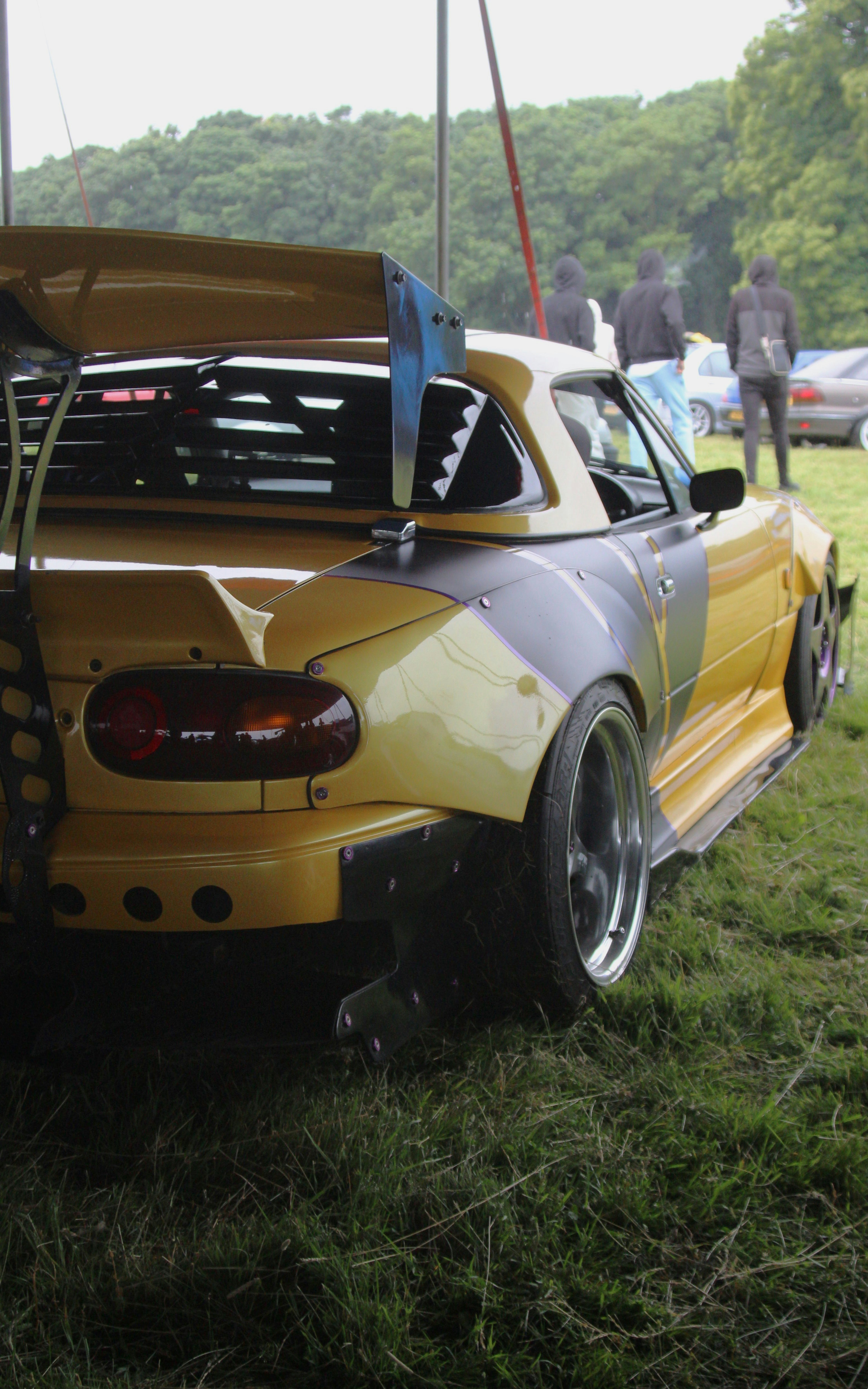 A yellow car parked on top of a lush green field