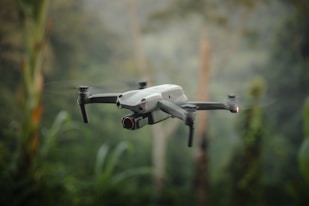 A white and black remote controlled flying over a forest