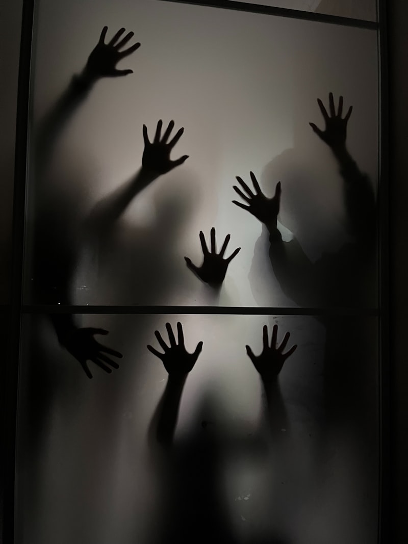 Shadows of multiple hands pressed against frosted glass