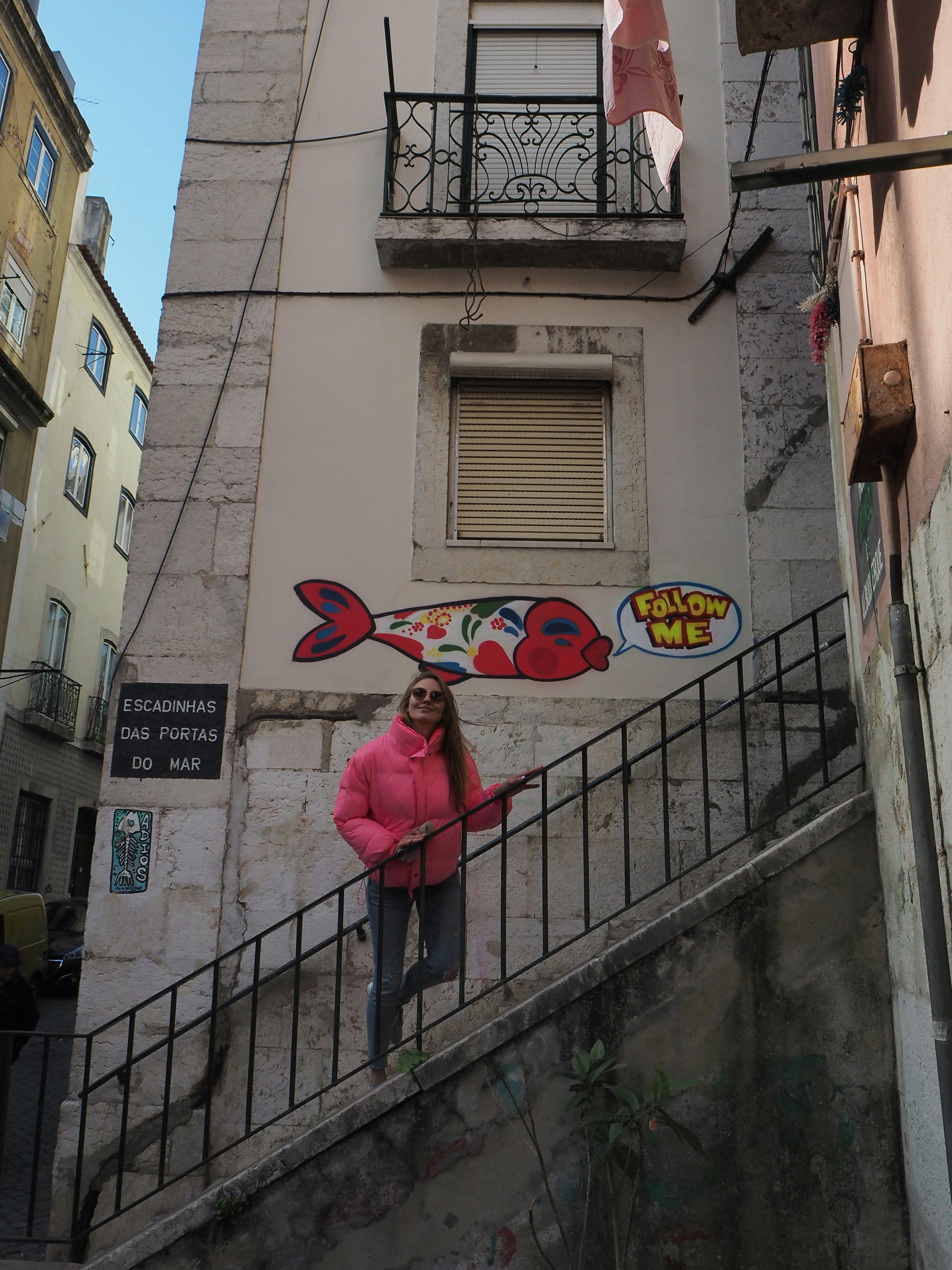 Una mujer con una chaqueta rosa de pie en una escalera