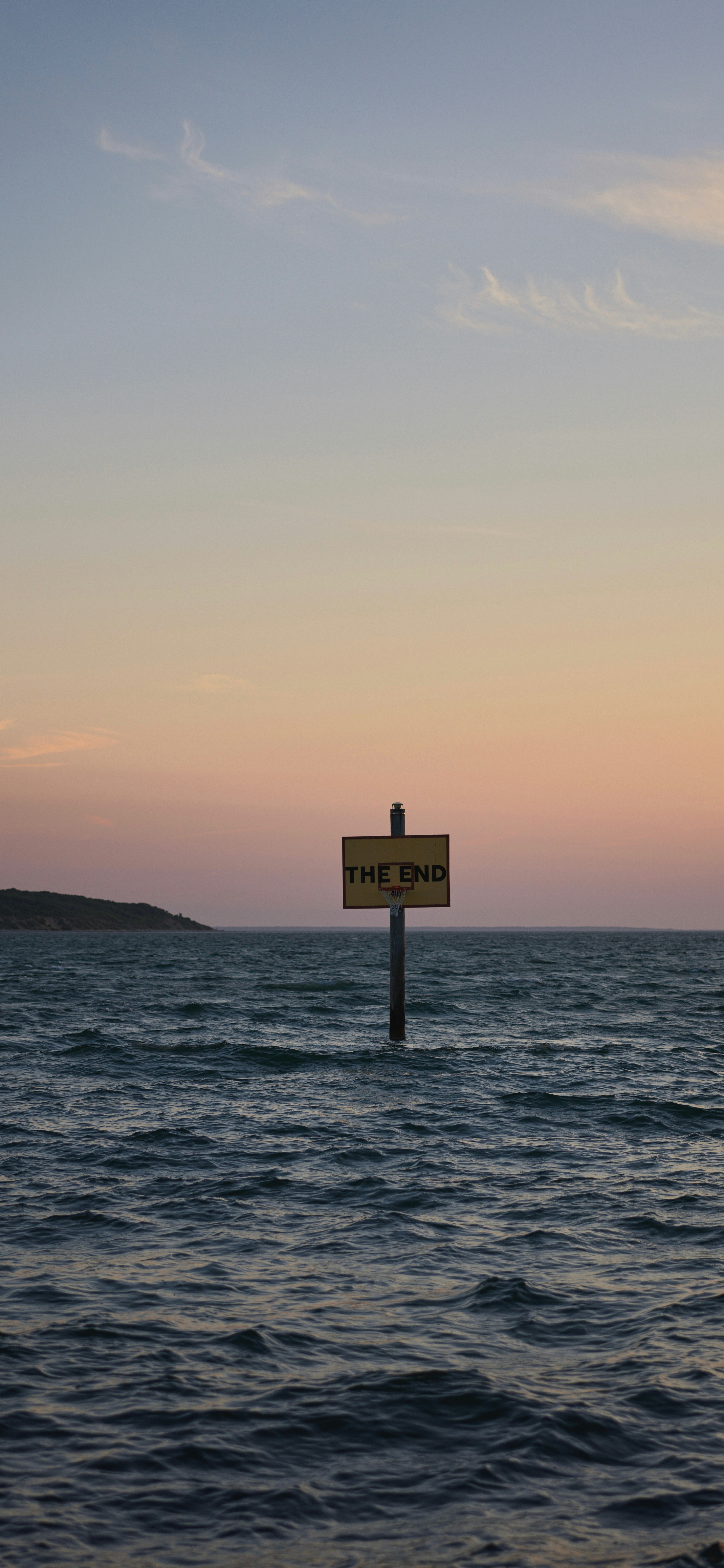 A sign on a pole in the middle of the ocean