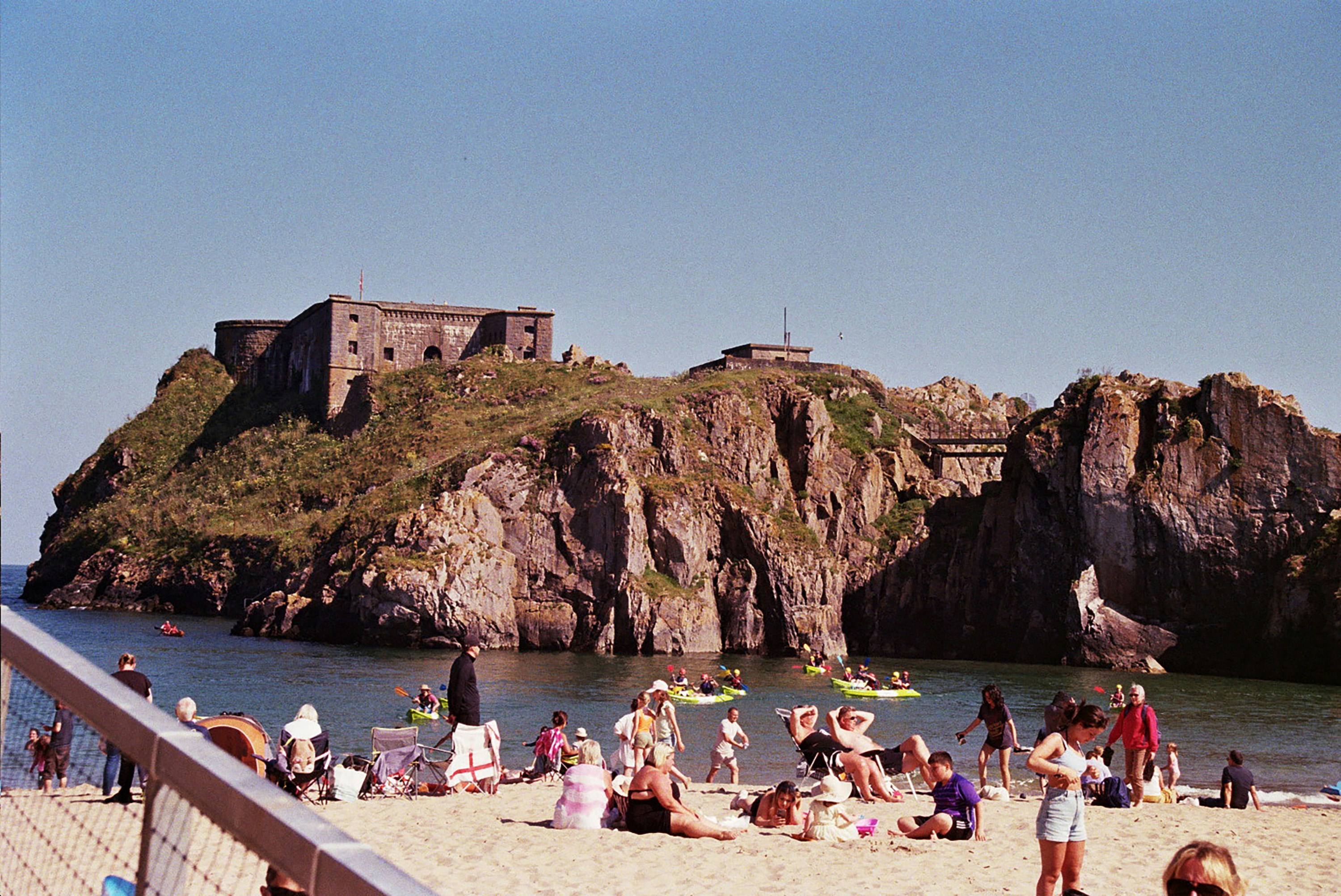 A group of people sitting on top of a sandy beach