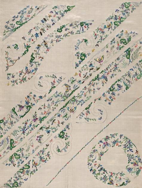 White fabric with delicate floral embroidered patterns — a close study in Chinese textile craft tradition, highlighting the precision of thread placement on woven ground.