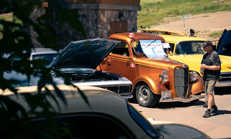 A man standing next to a bright yellow classic car, showing the kind of owner conversations visitors can have at Henderson Hot Rod Days
