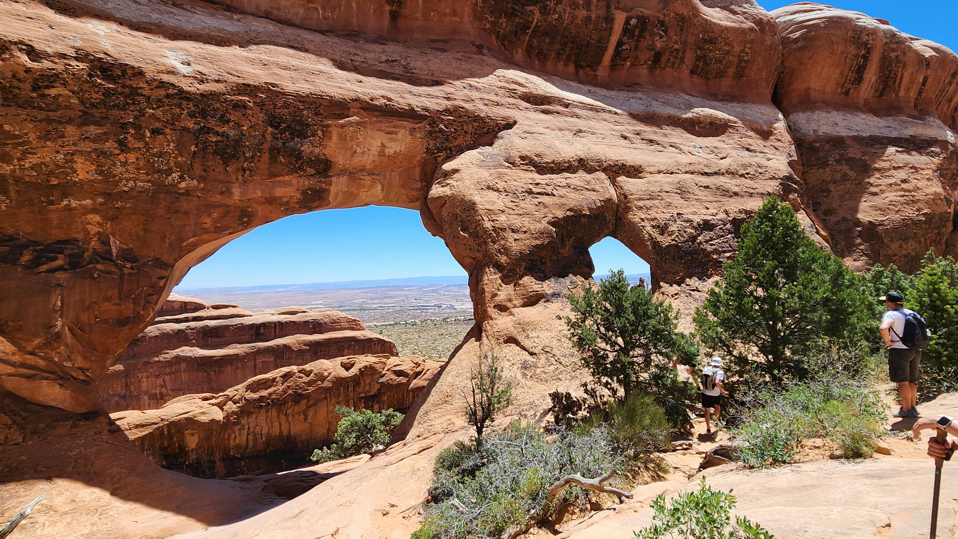 A man is standing in front of a rock formation, Partition Arch is a window-like arch in the Devil