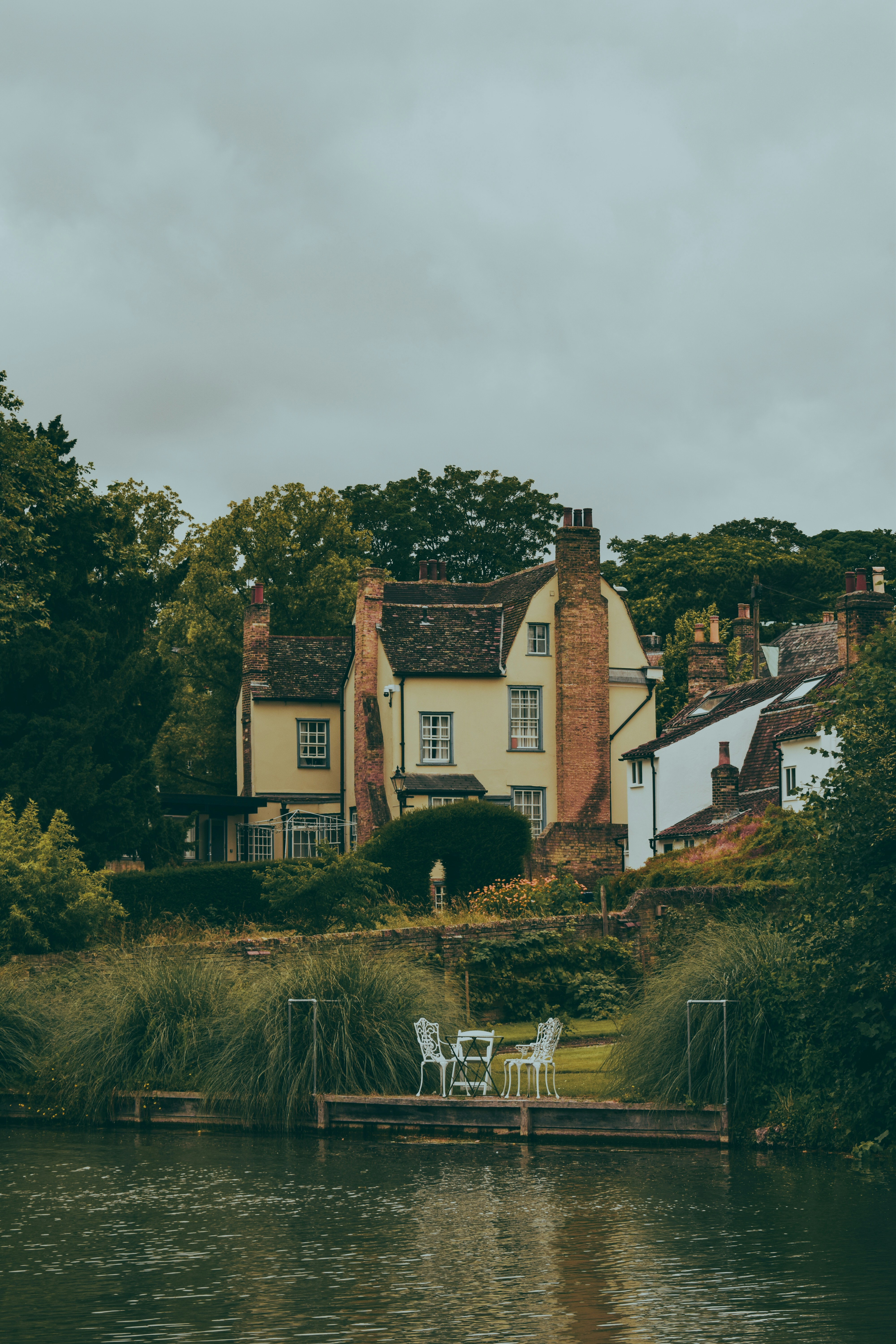 A house sitting on top of a lush green hillside next to a lake
