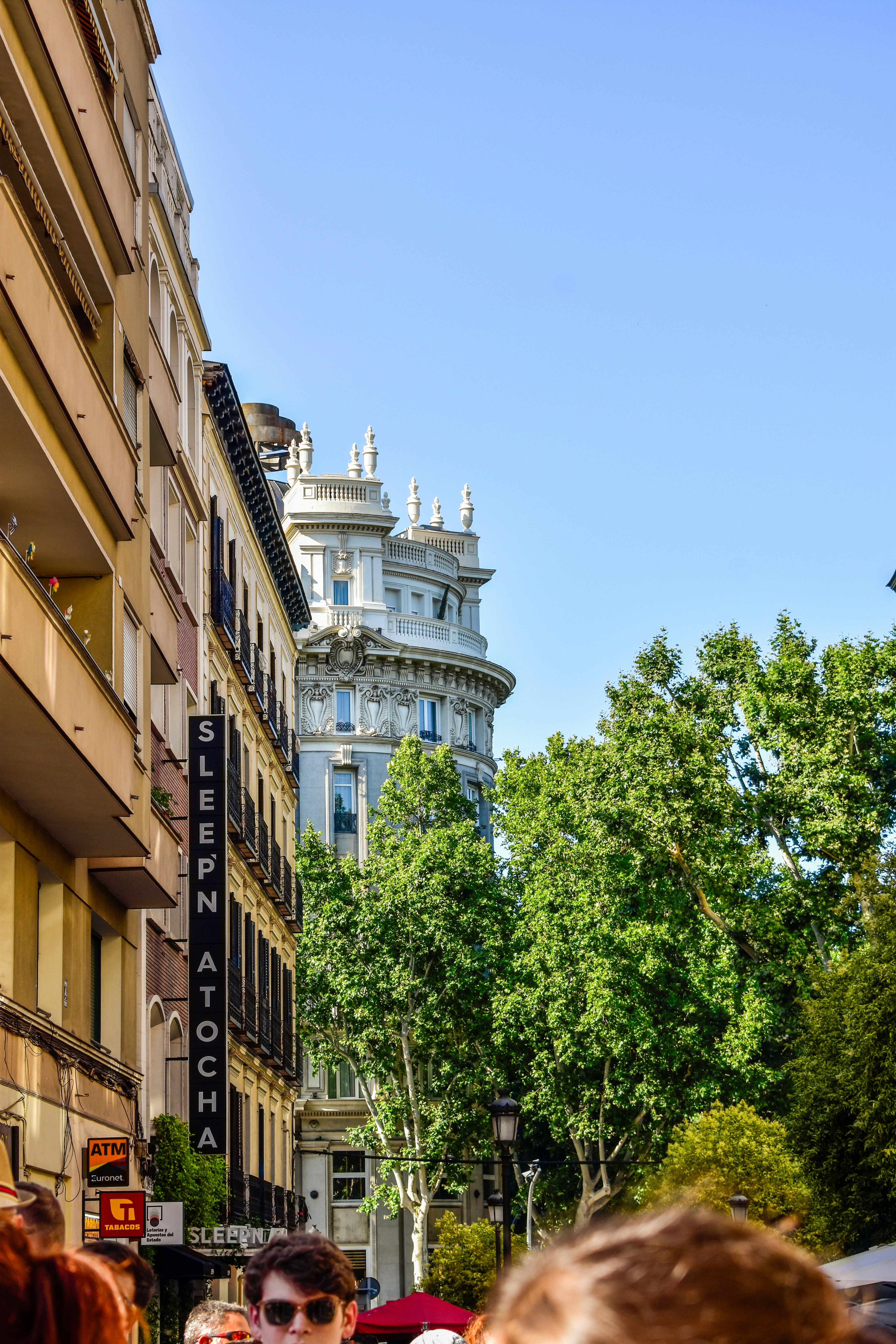 A group of people walking down a street next to tall buildings