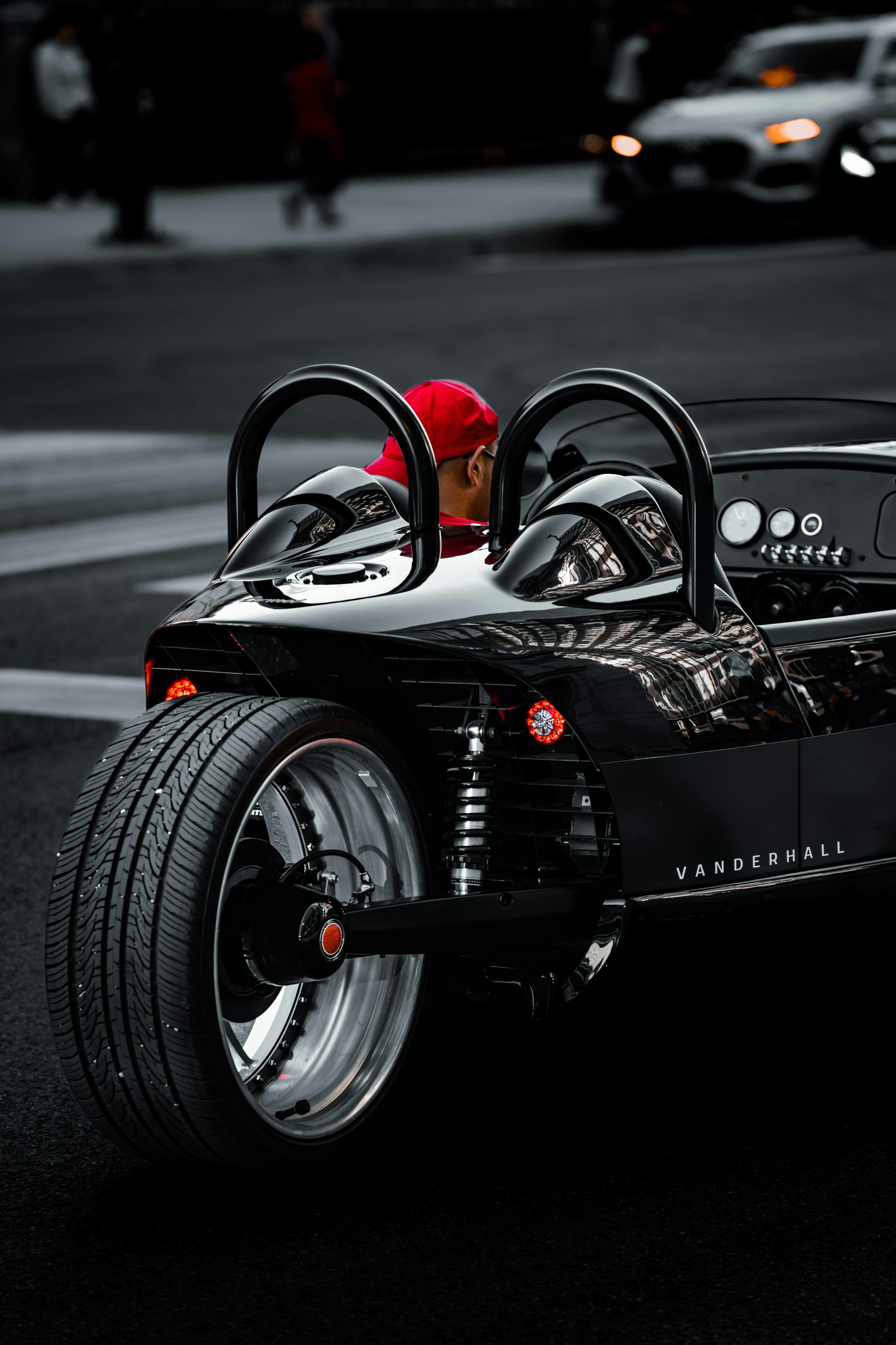 A man in a red hat is driving a black car