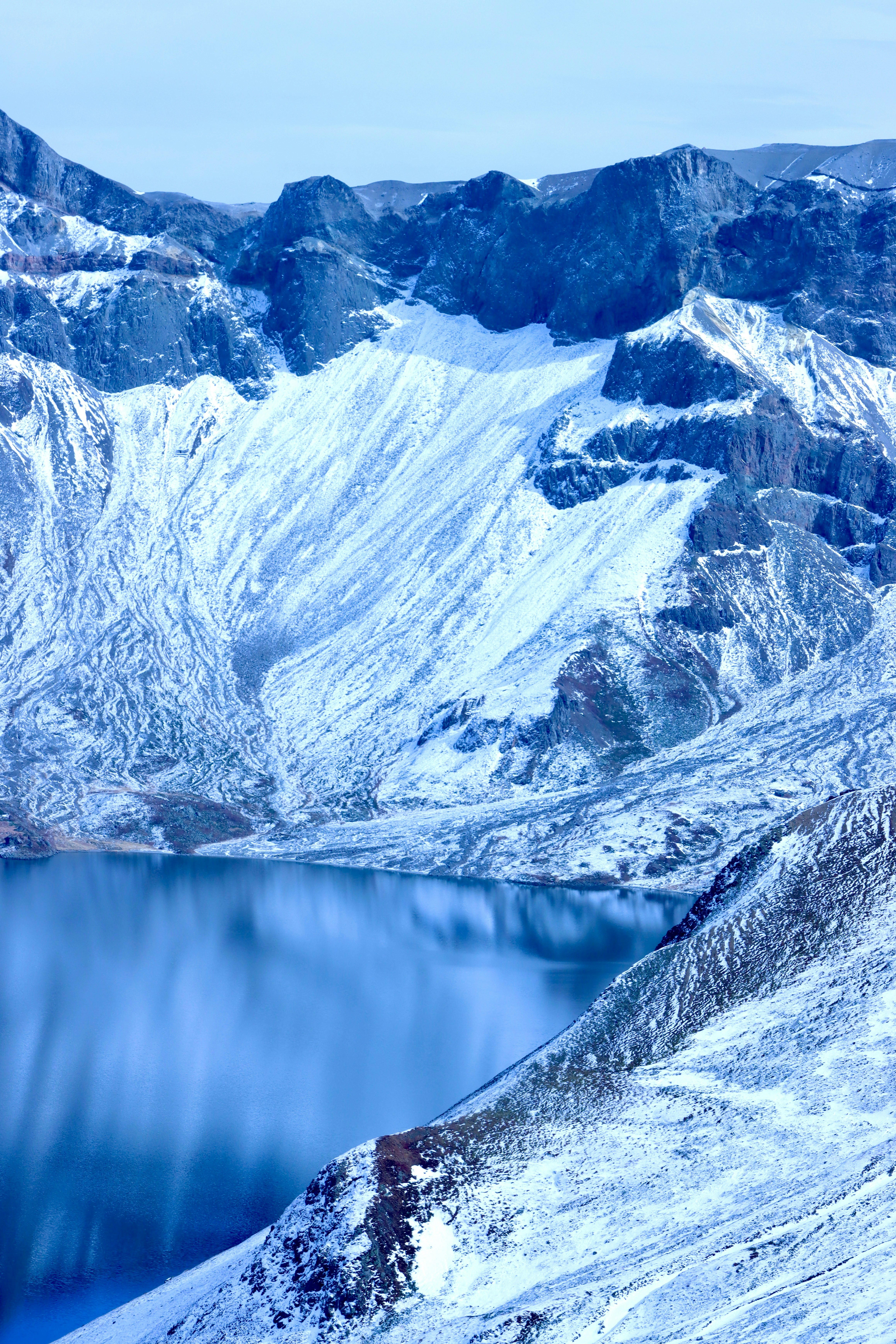 A snow covered mountain with a lake in the middle