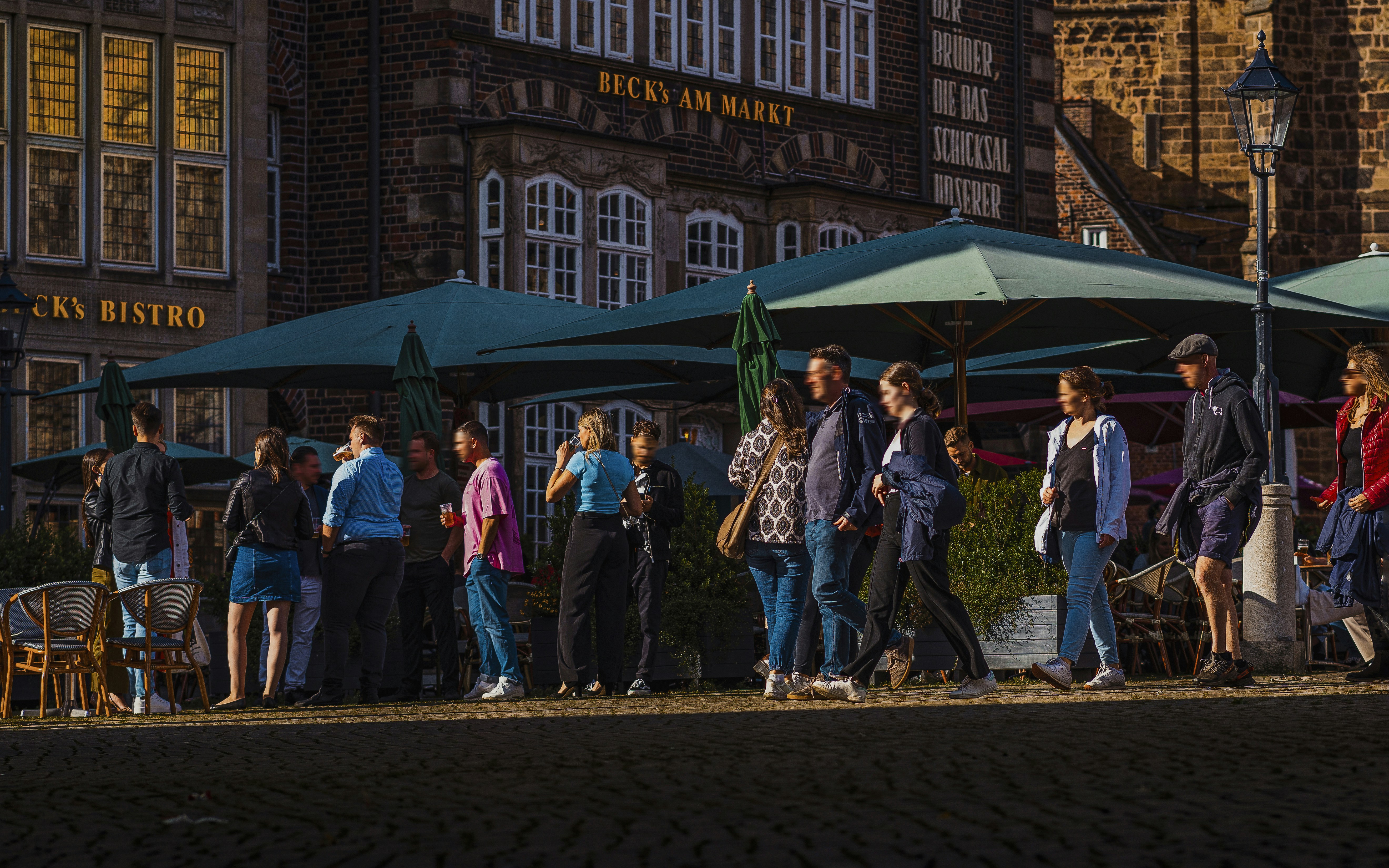 A group of people walking down a street next to tall buildings