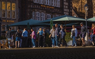 A group of people walking down a street next to tall buildings