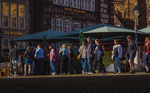 A group of people walking down a street next to tall buildings
