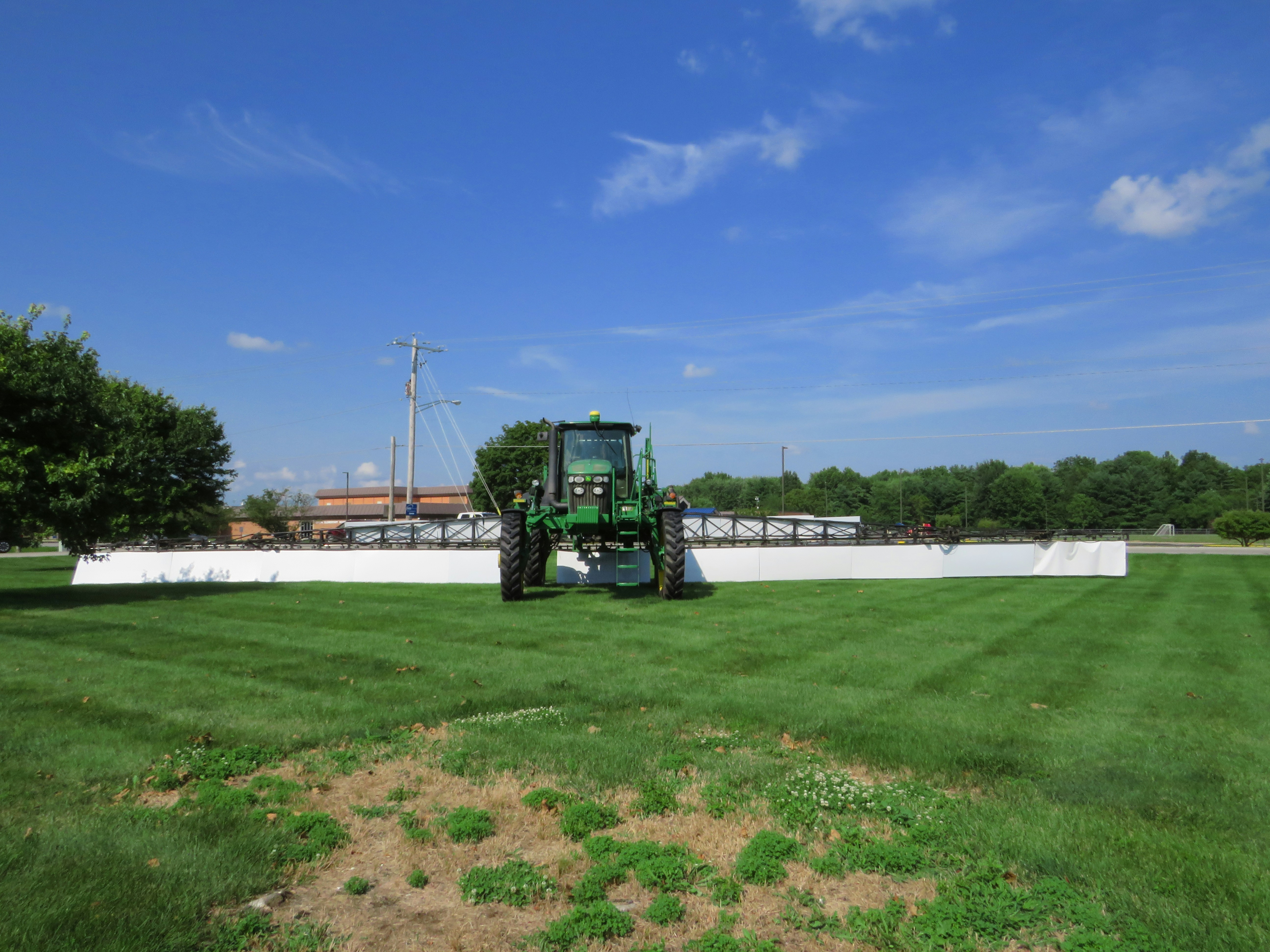 Agricultural tractor being cleaned with water spray in an open field setting