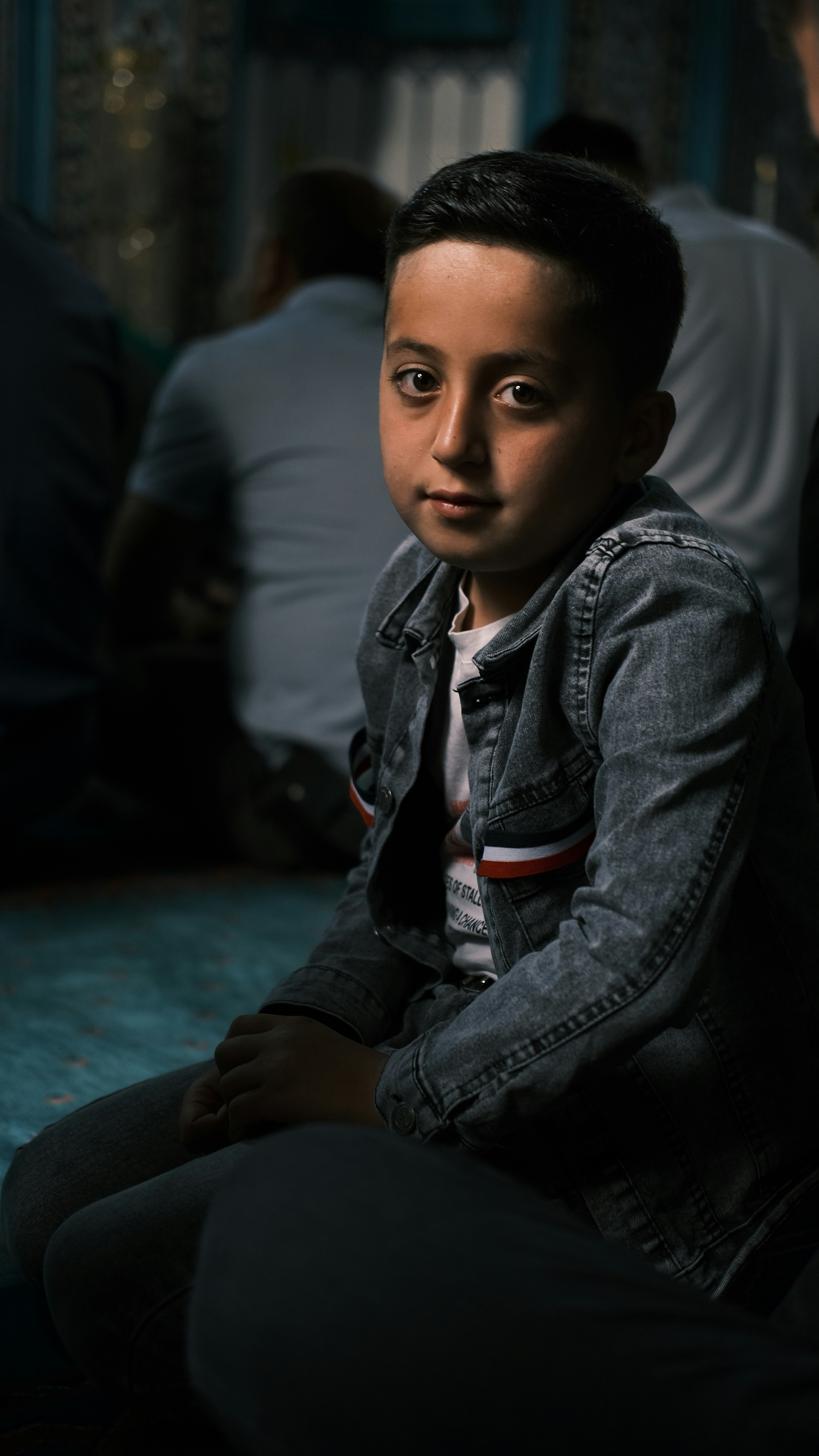 A young boy sitting on the floor in front of a group of people photo ...
