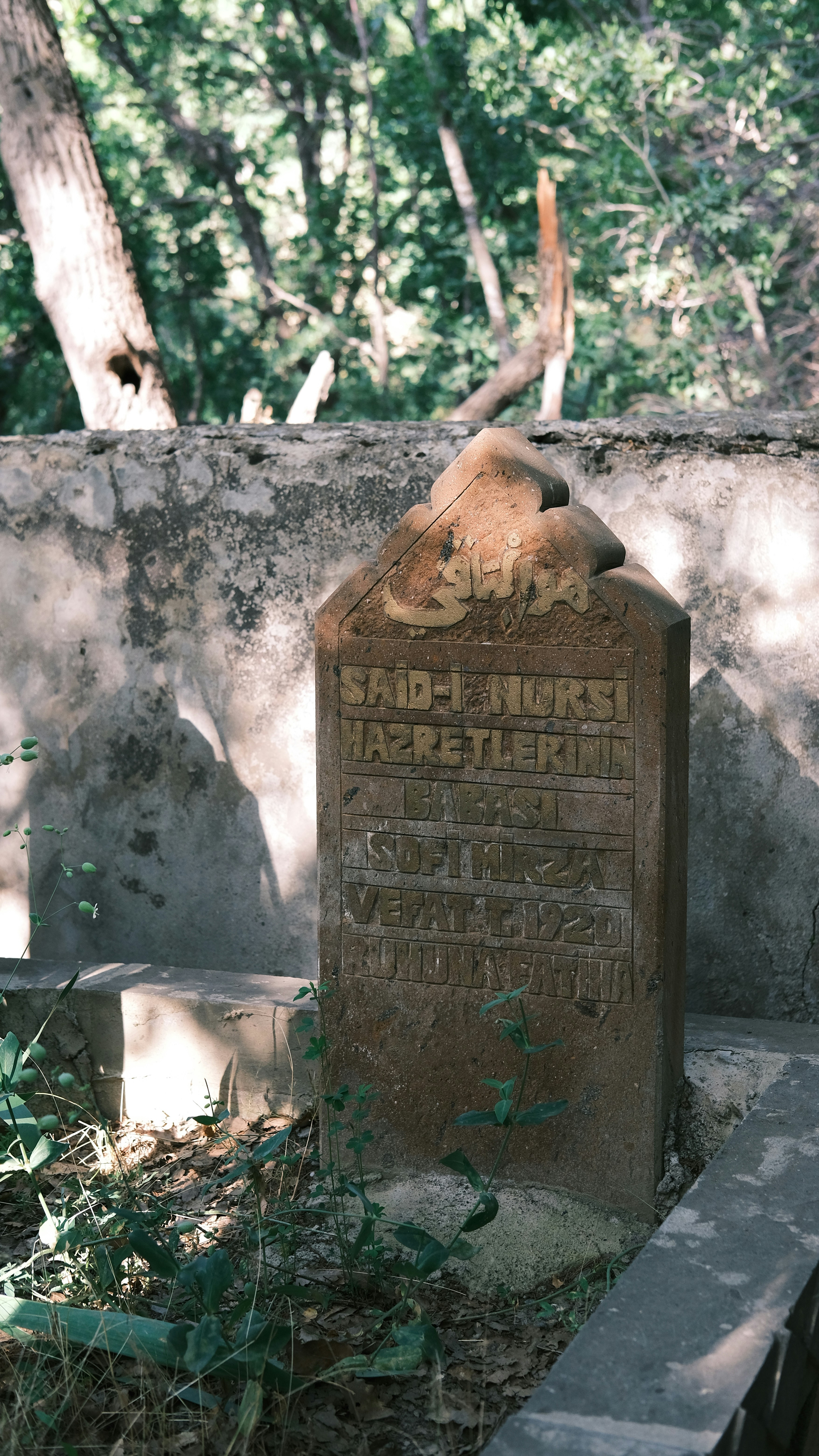 A headstone in a cemetery with trees in the background