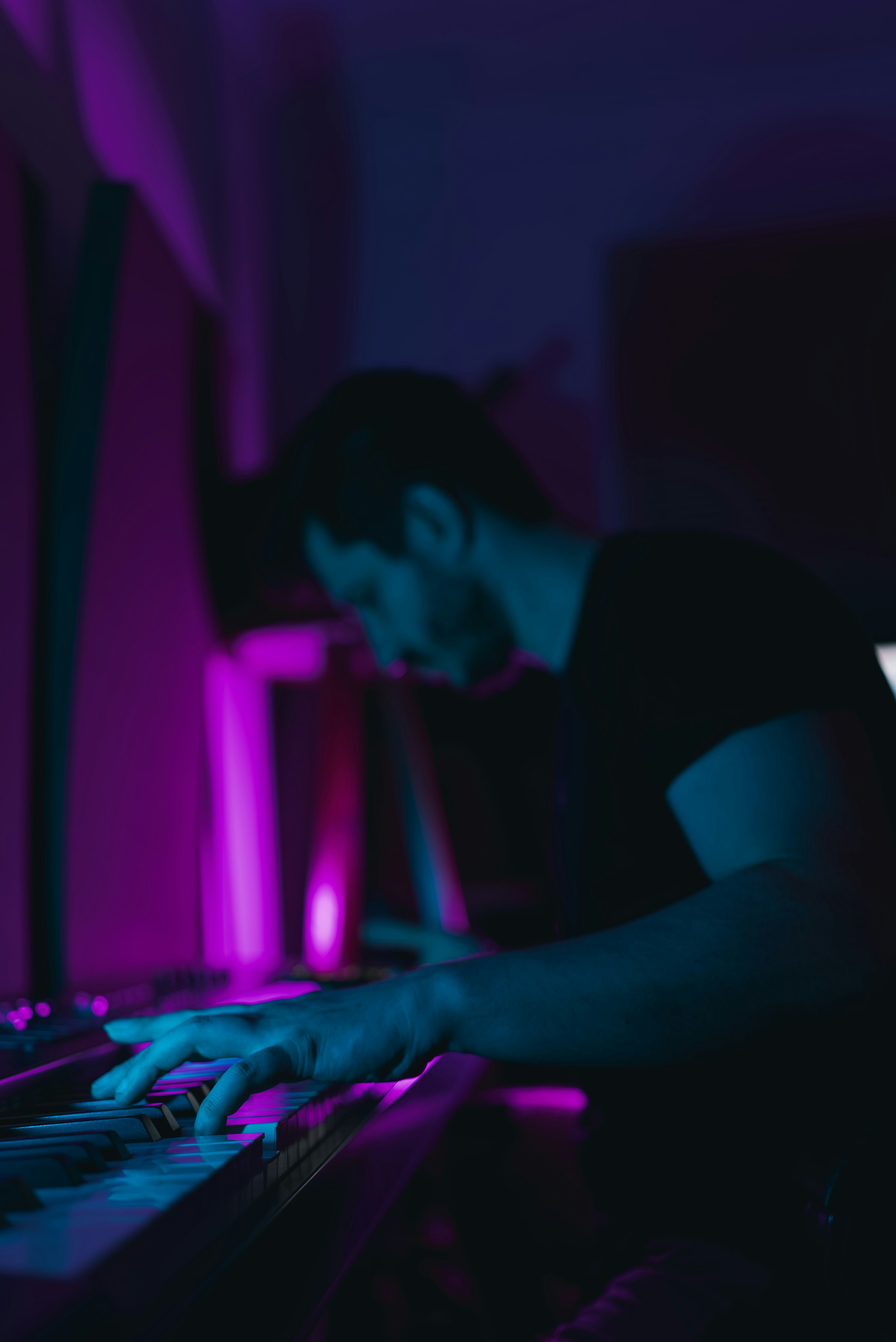A man sitting at a keyboard in a dark room