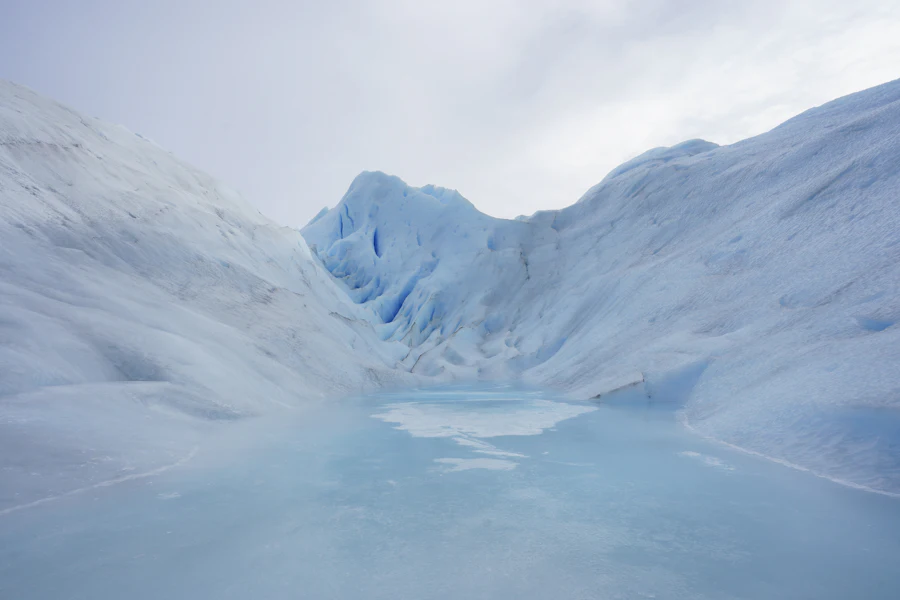 A broad glacier tongue spilling from a snow-covered mountain under flat grey light