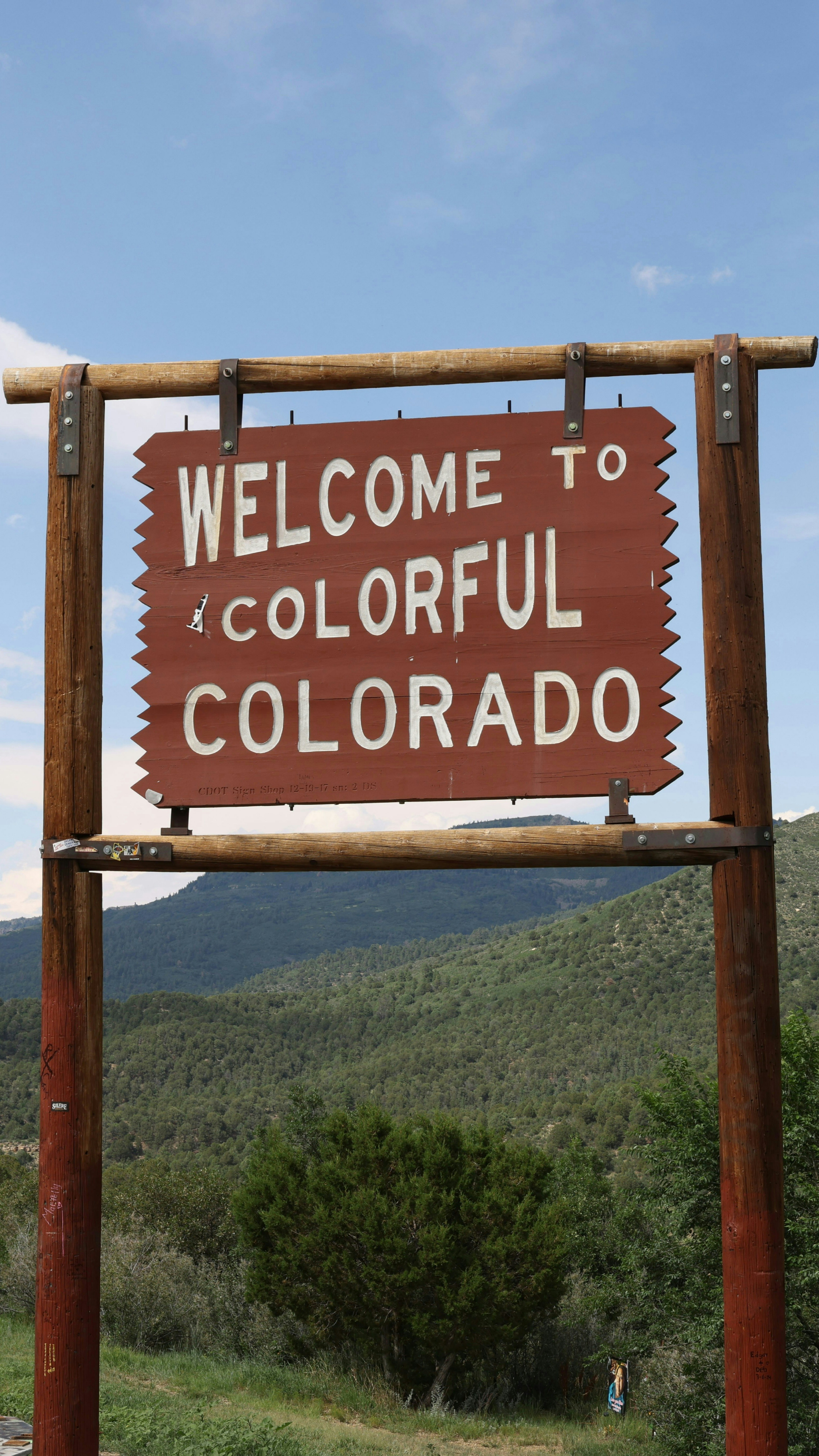 A welcome to colorful colorado sign in front of a mountain