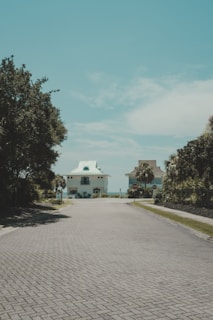 A brick road with a white house in the distance