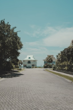 A brick road with a white house in the distance