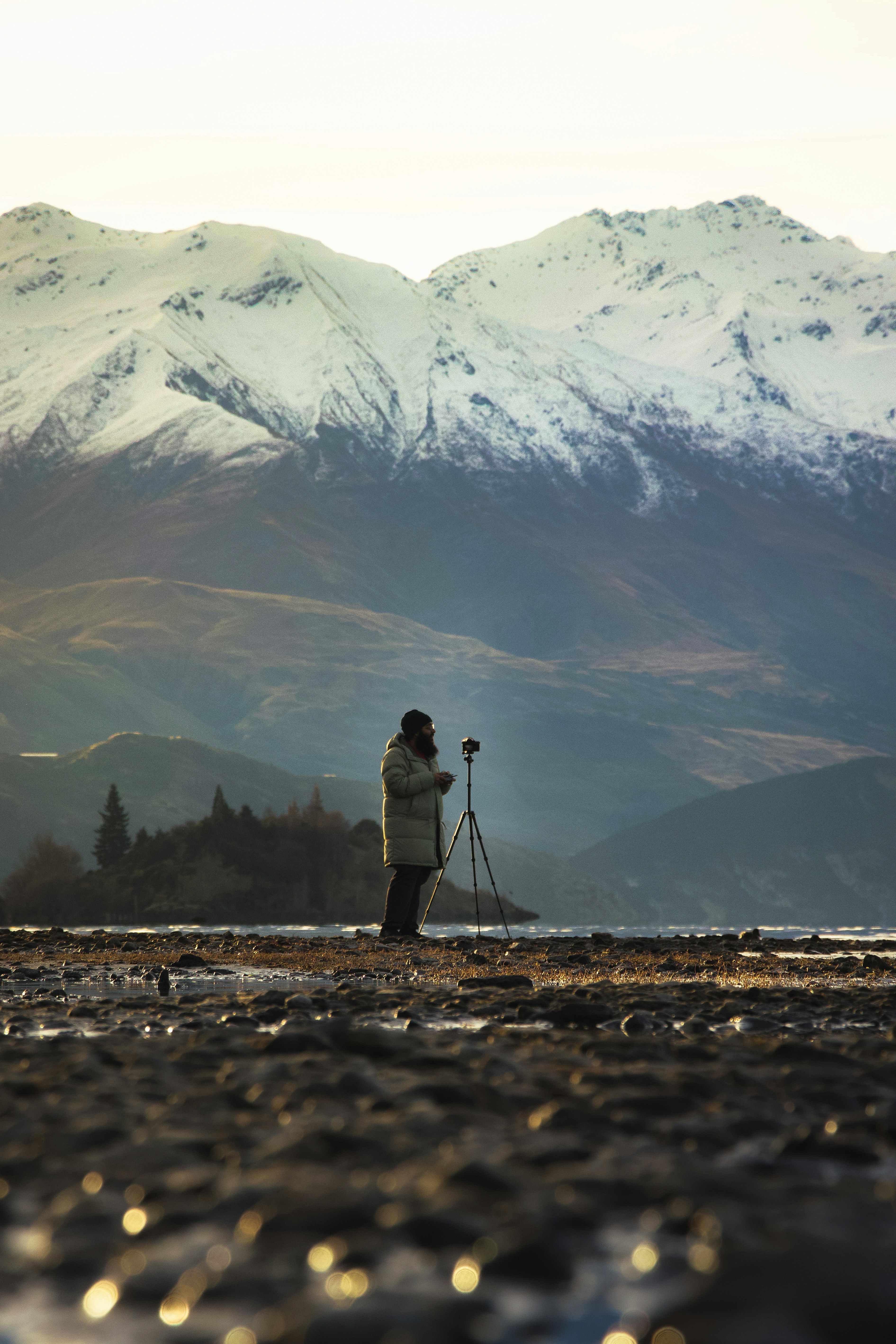 A person with a camera standing in front of a mountain