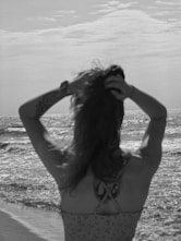 A woman standing on top of a beach next to the ocean